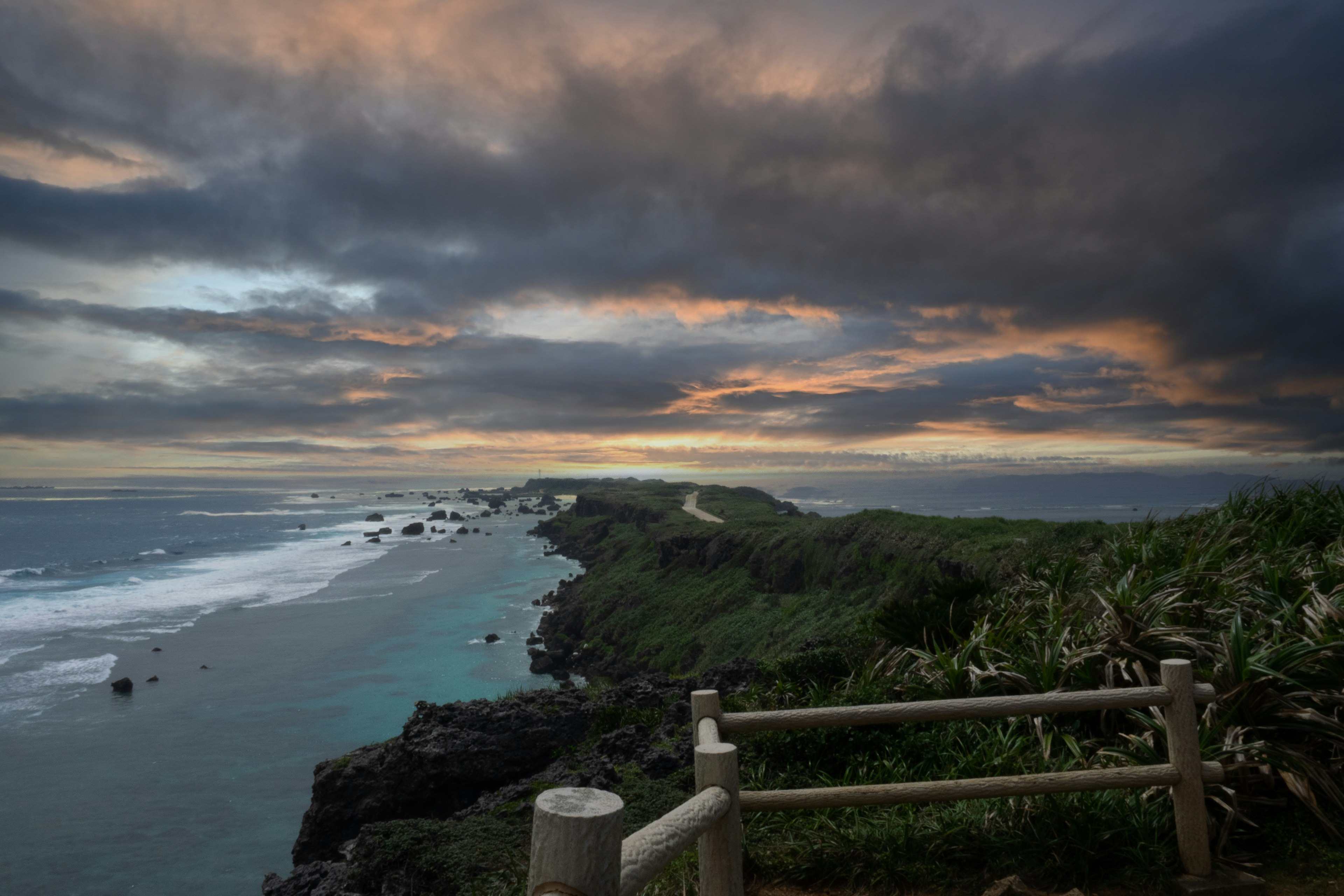 Vista costiera con un drammatico tramonto su scogliere e oceano