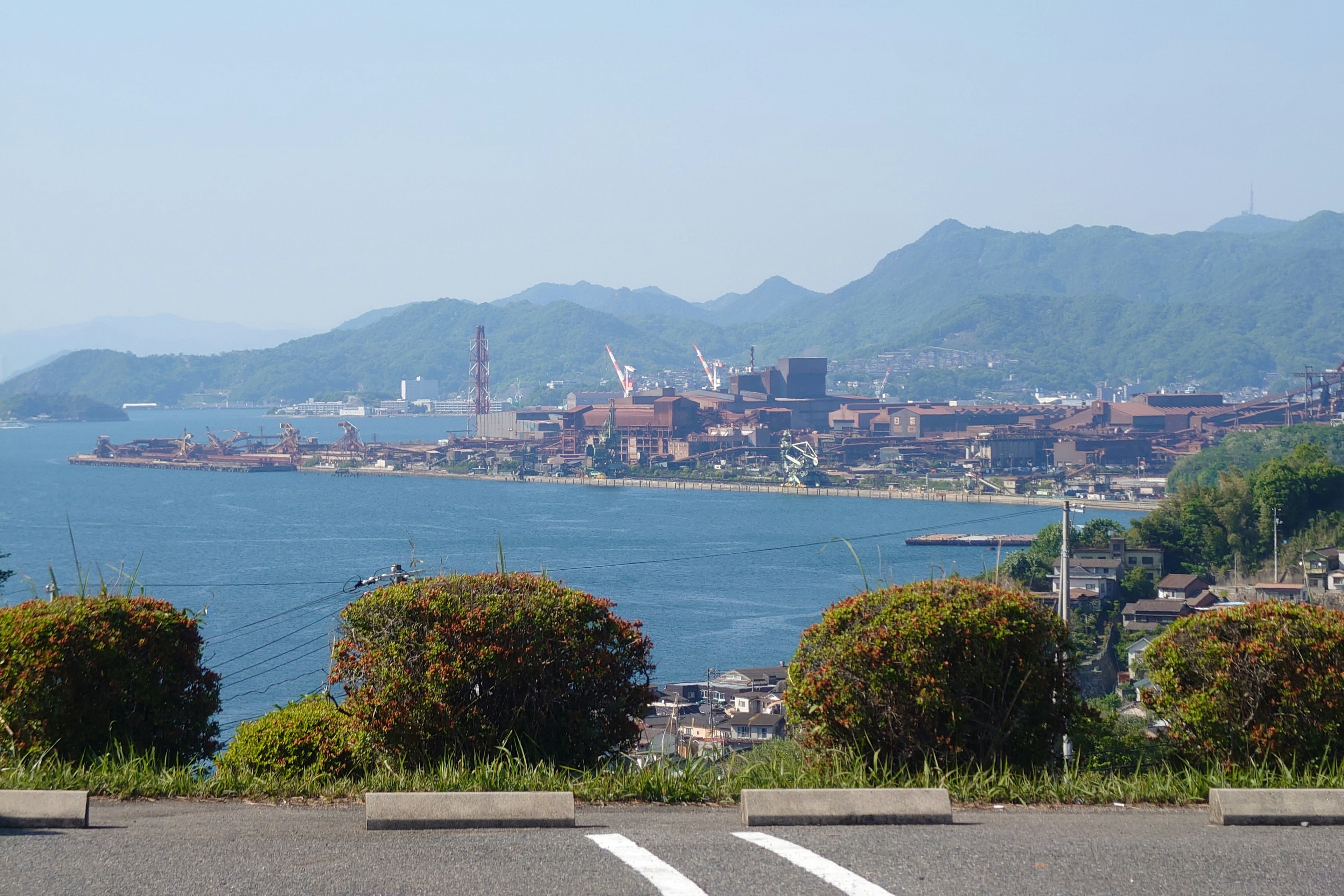 Vista panoramica dell'oceano blu e delle montagne con edifici industriali