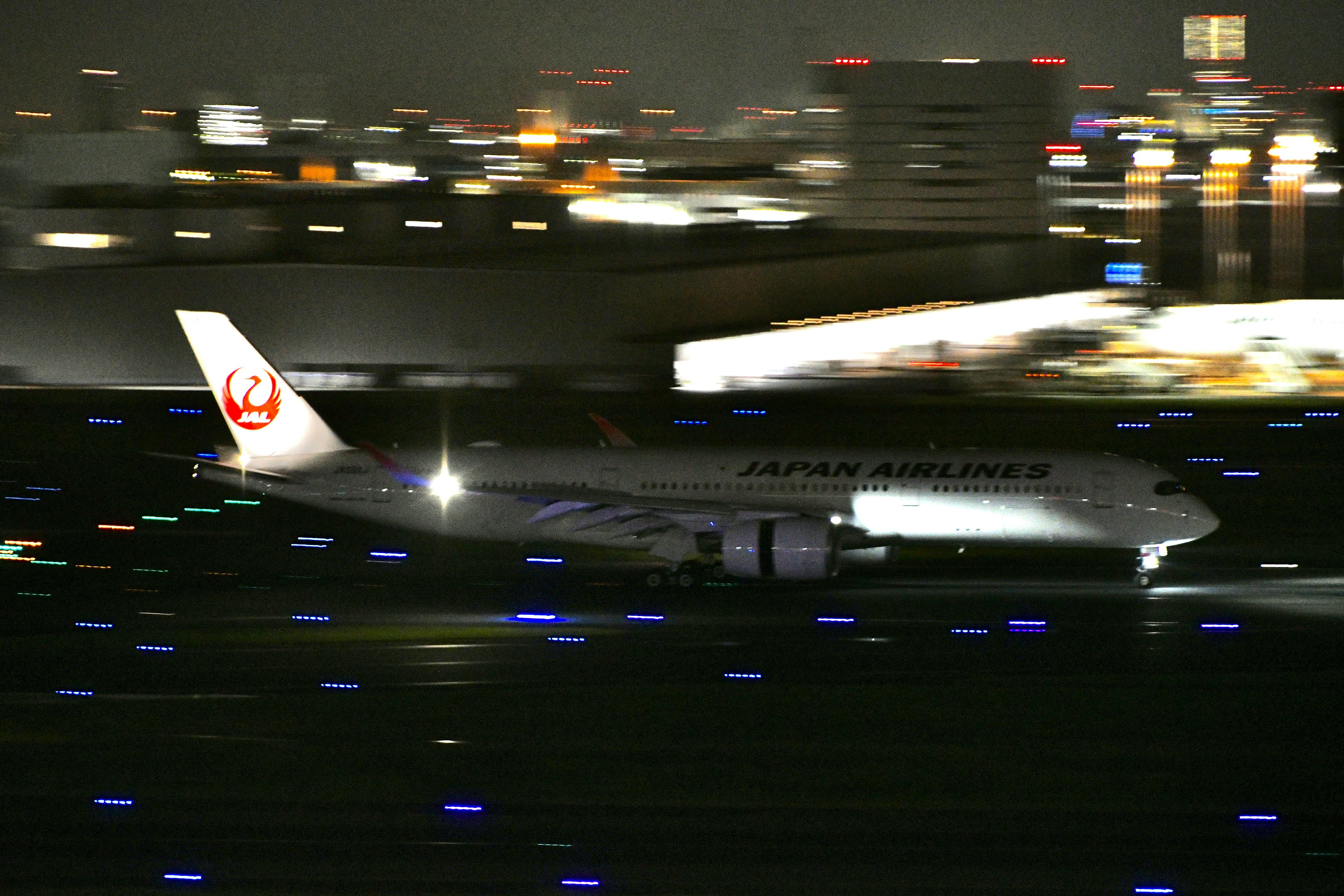 Japan Airlines aircraft taxiing on runway at night