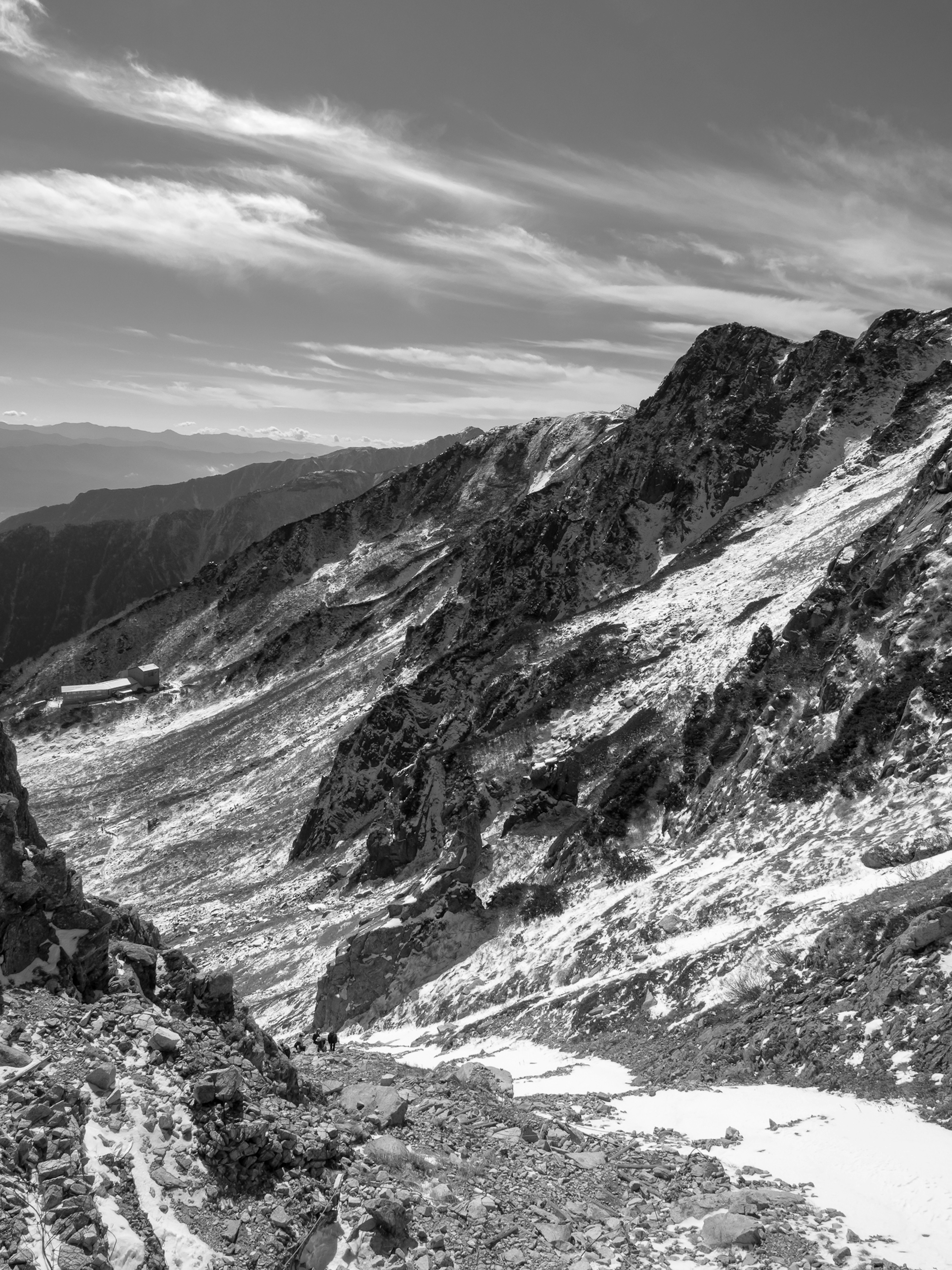 Paysage montagneux en noir et blanc avec des falaises abruptes et des couches rocheuses montagnes lointaines et nuages