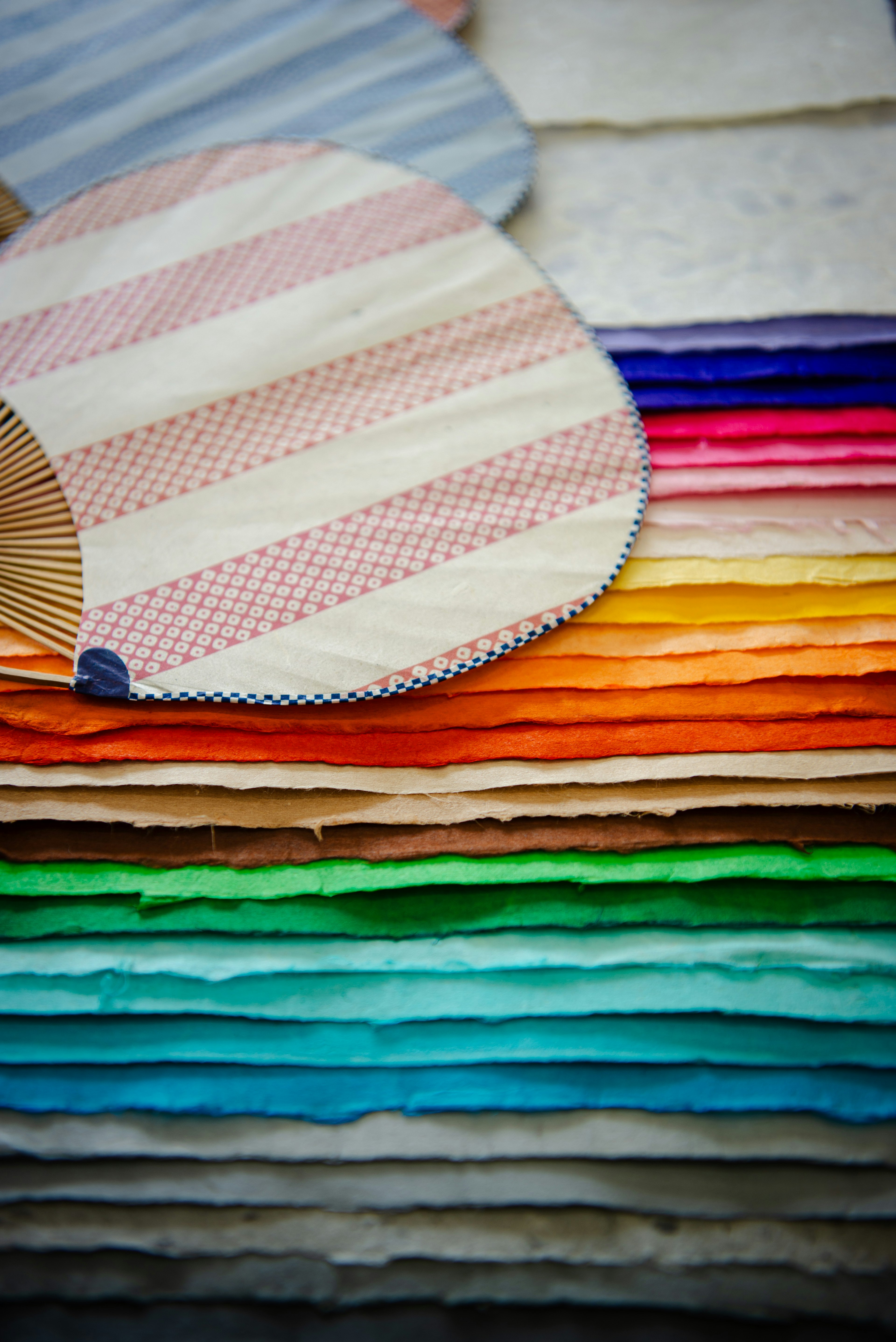 A stack of colorful paper with a striped fan placed on top