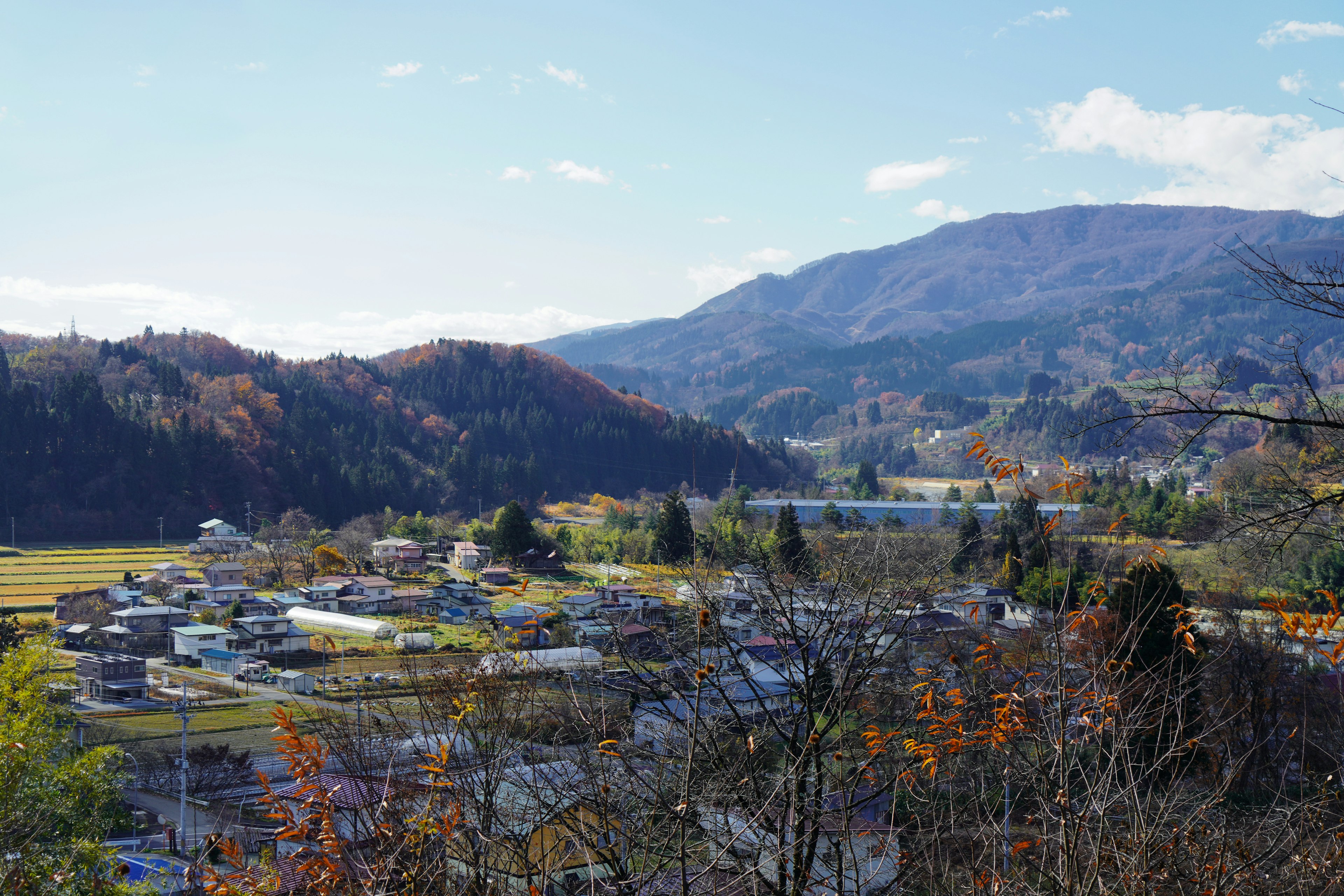 Landschaft mit Häusern umgeben von Bergen im Herbst