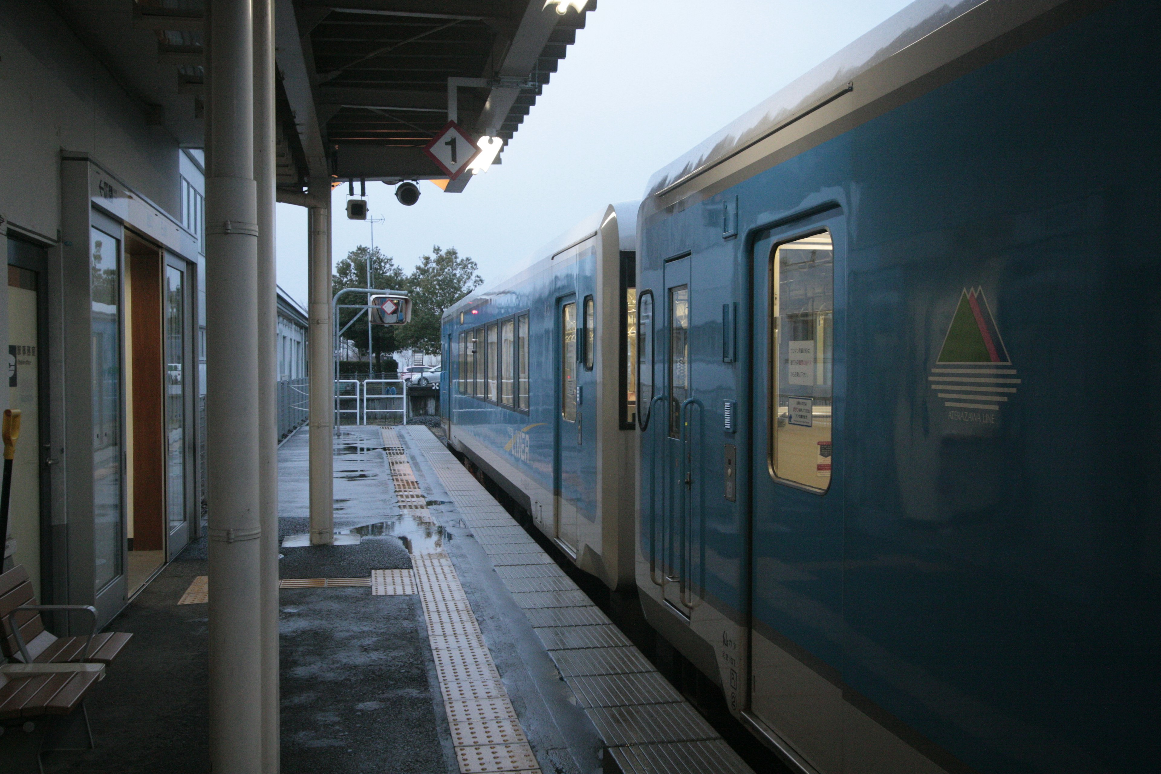 青い列車が駅のプラットフォームに停車中の風景