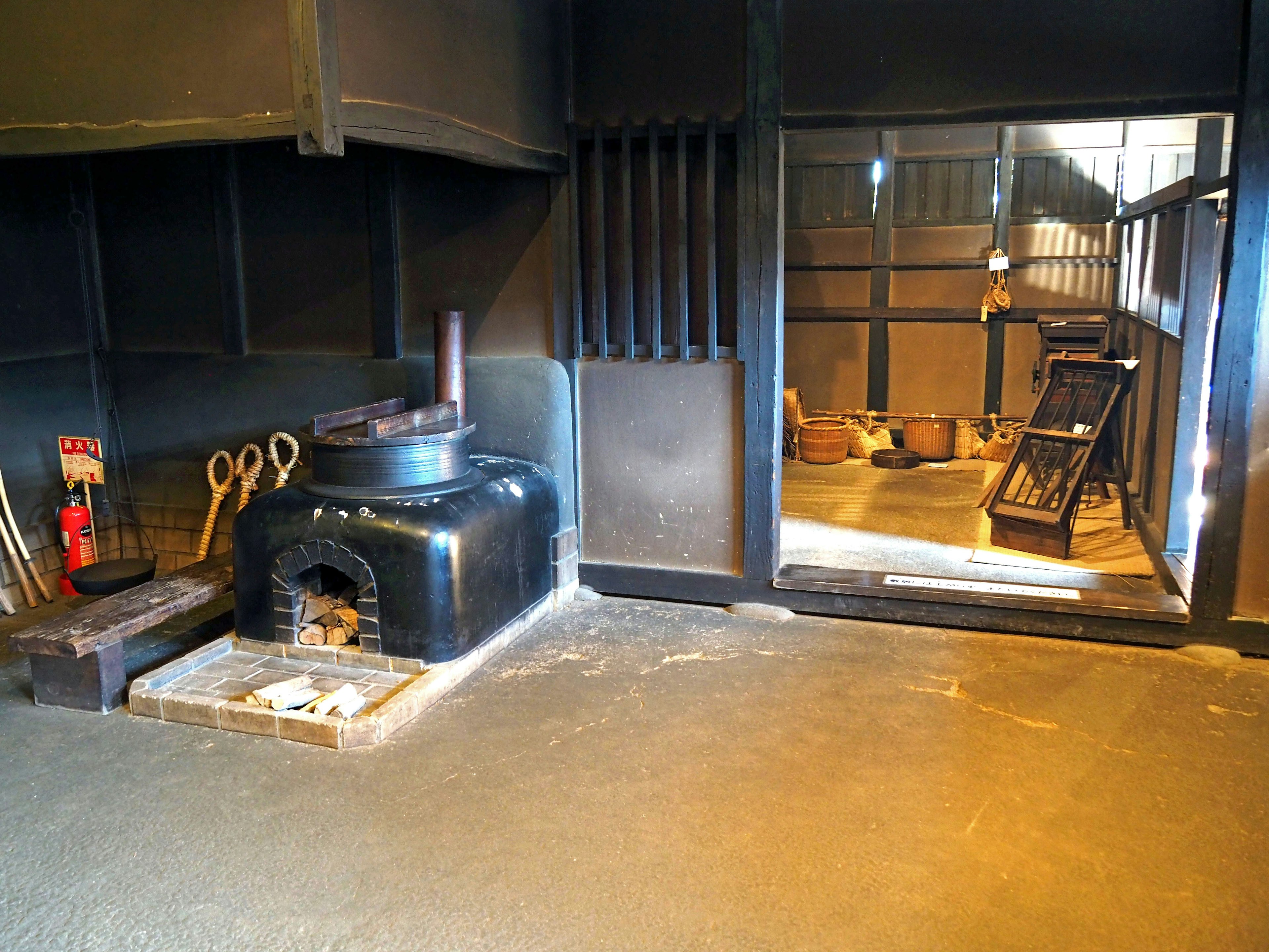 Interior of a traditional Japanese house featuring a black stove and wooden tools