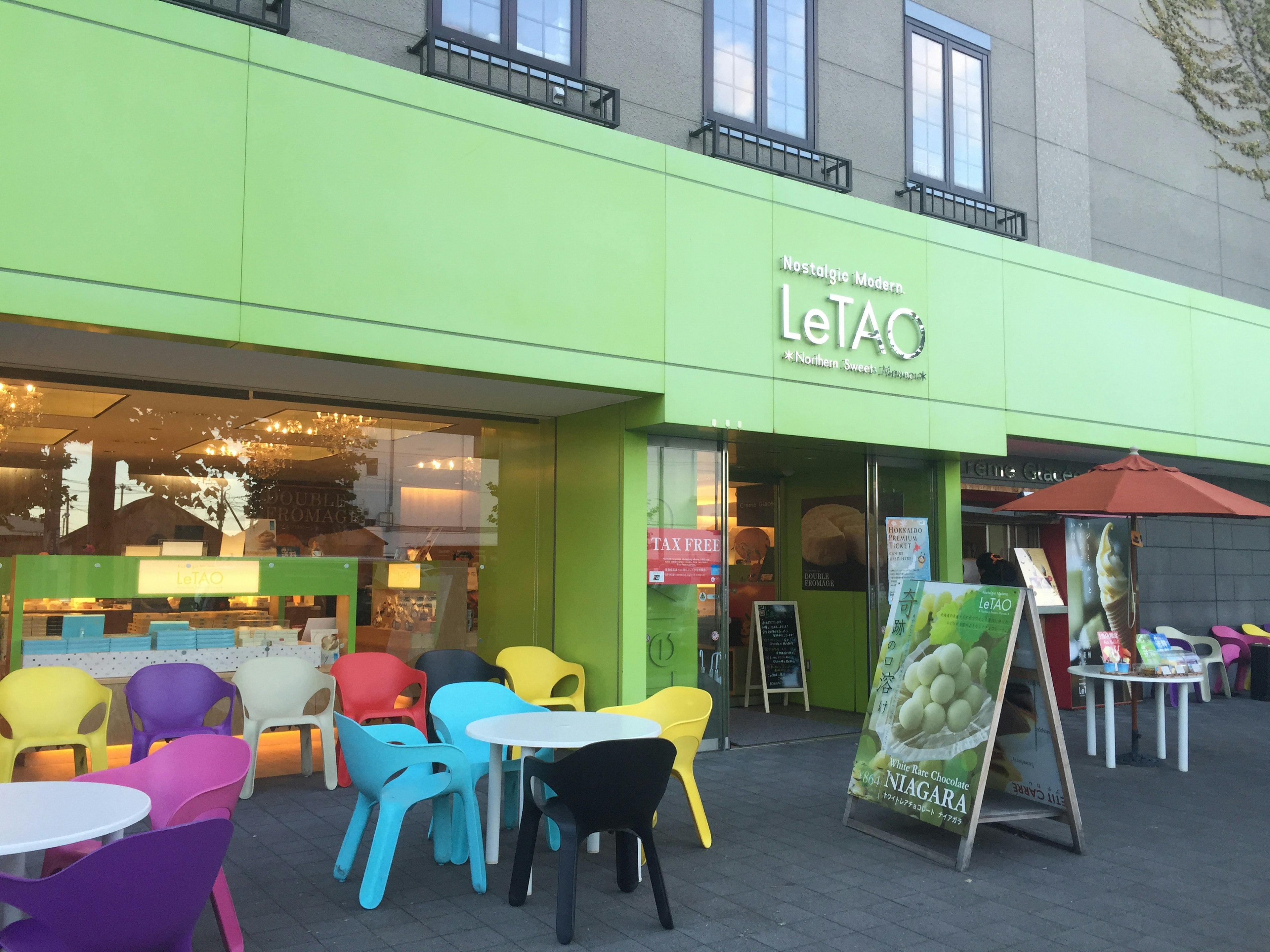 Entrée d'un café avec des chaises colorées et une façade verte