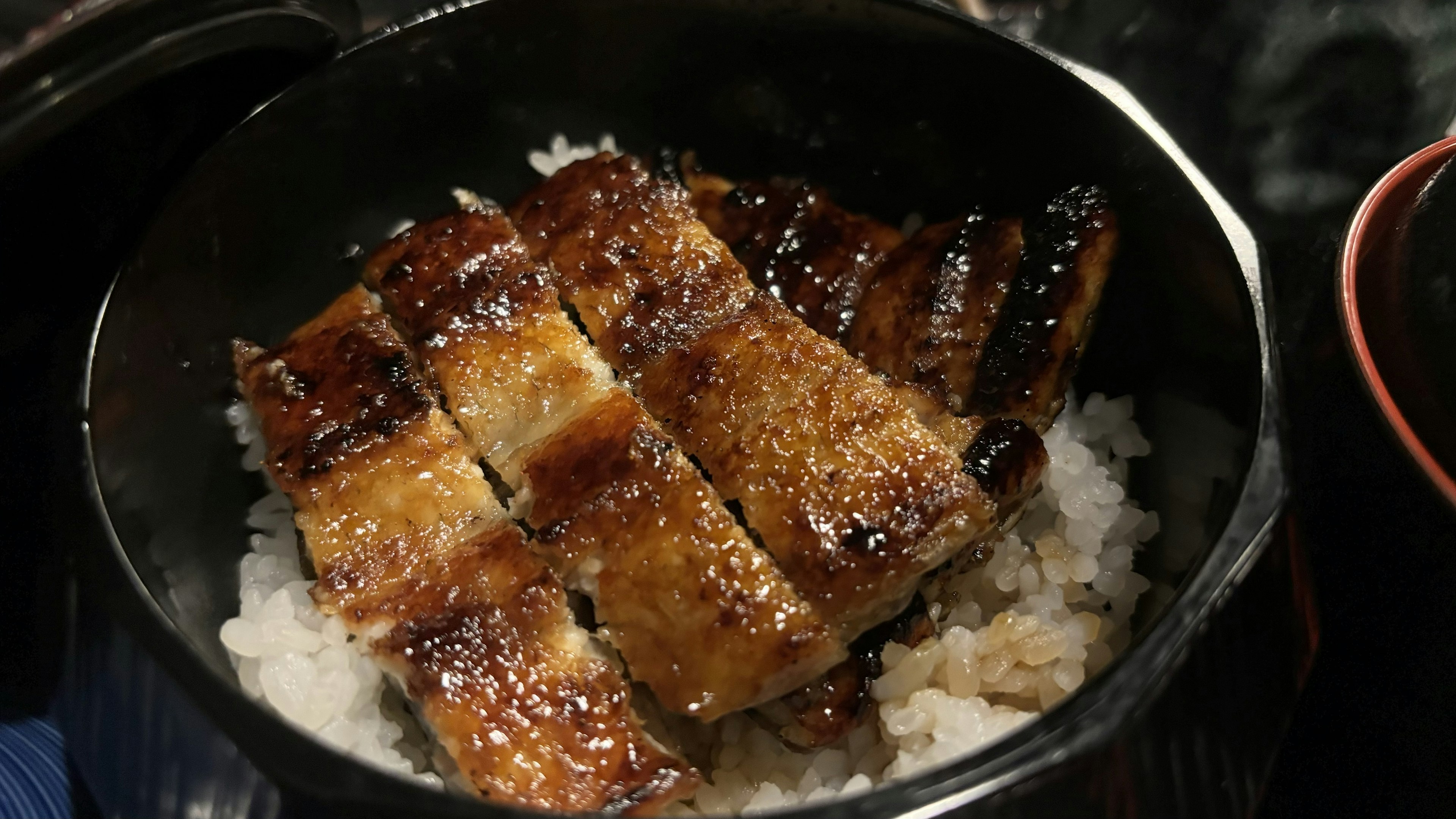 Anguila a la parrilla servida sobre arroz blanco en un tazón