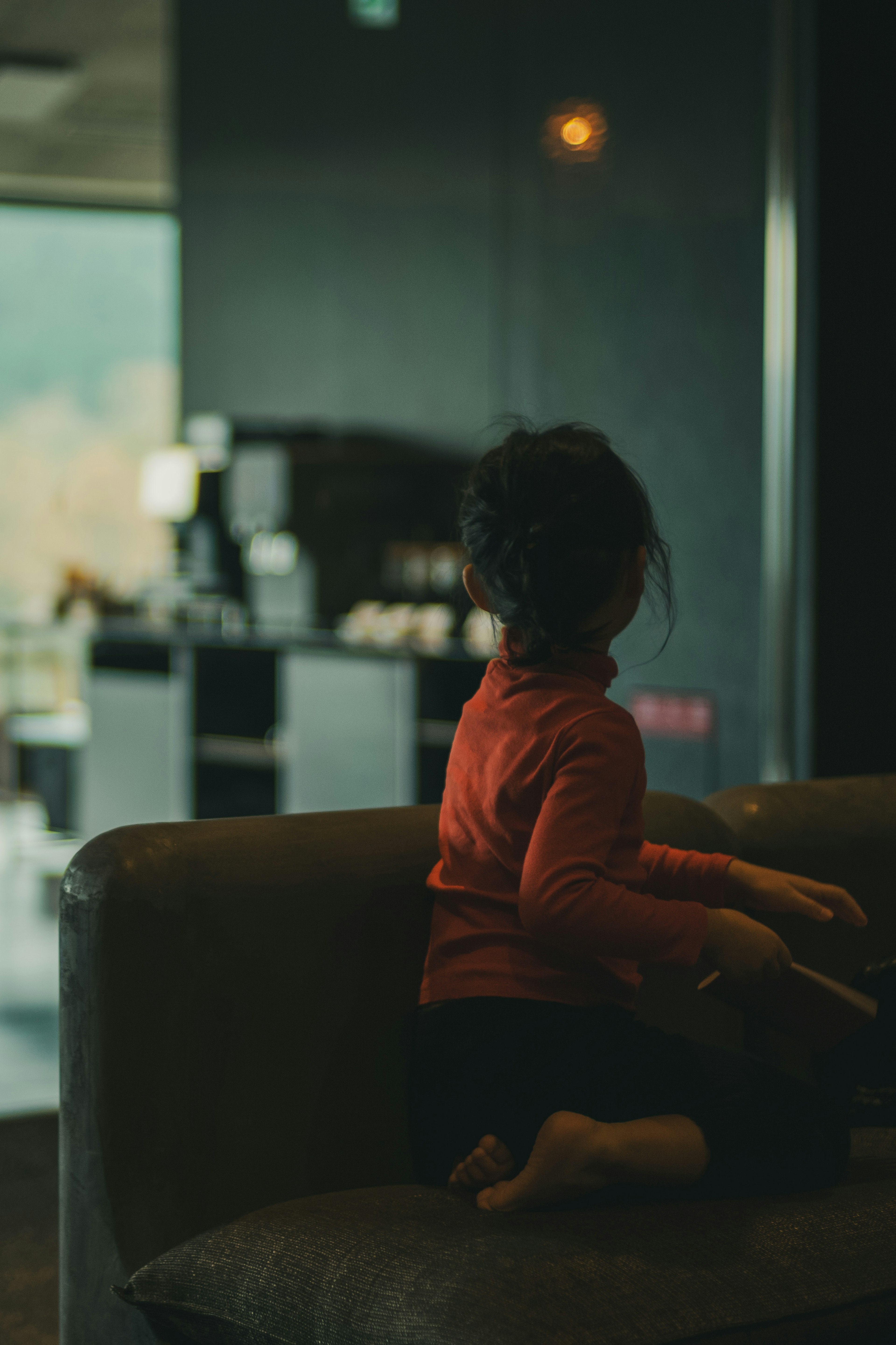 Child sitting on a sofa in a dark indoor setting