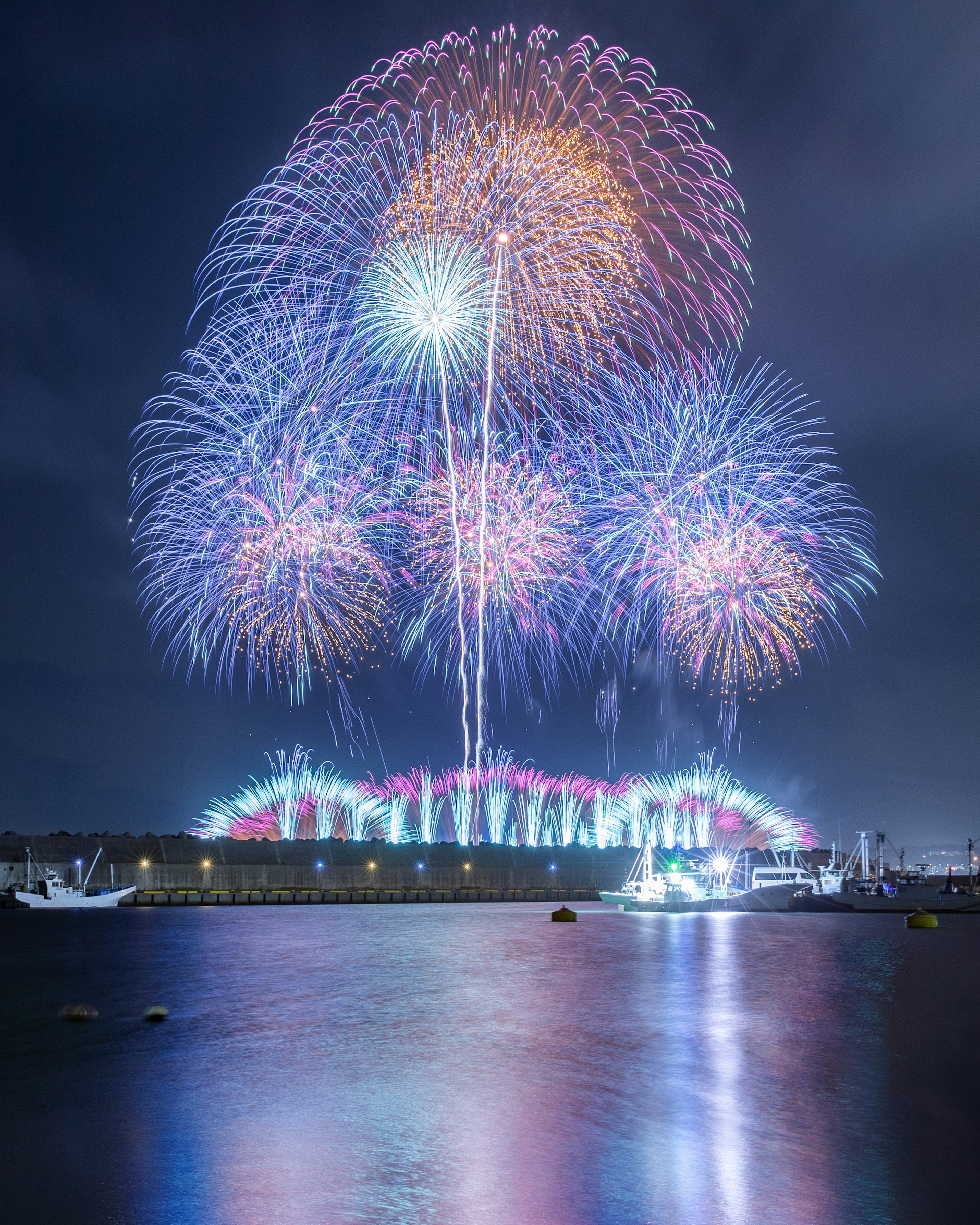 Fuochi d'artificio colorati illuminano il cielo notturno riflettendosi sull'acqua