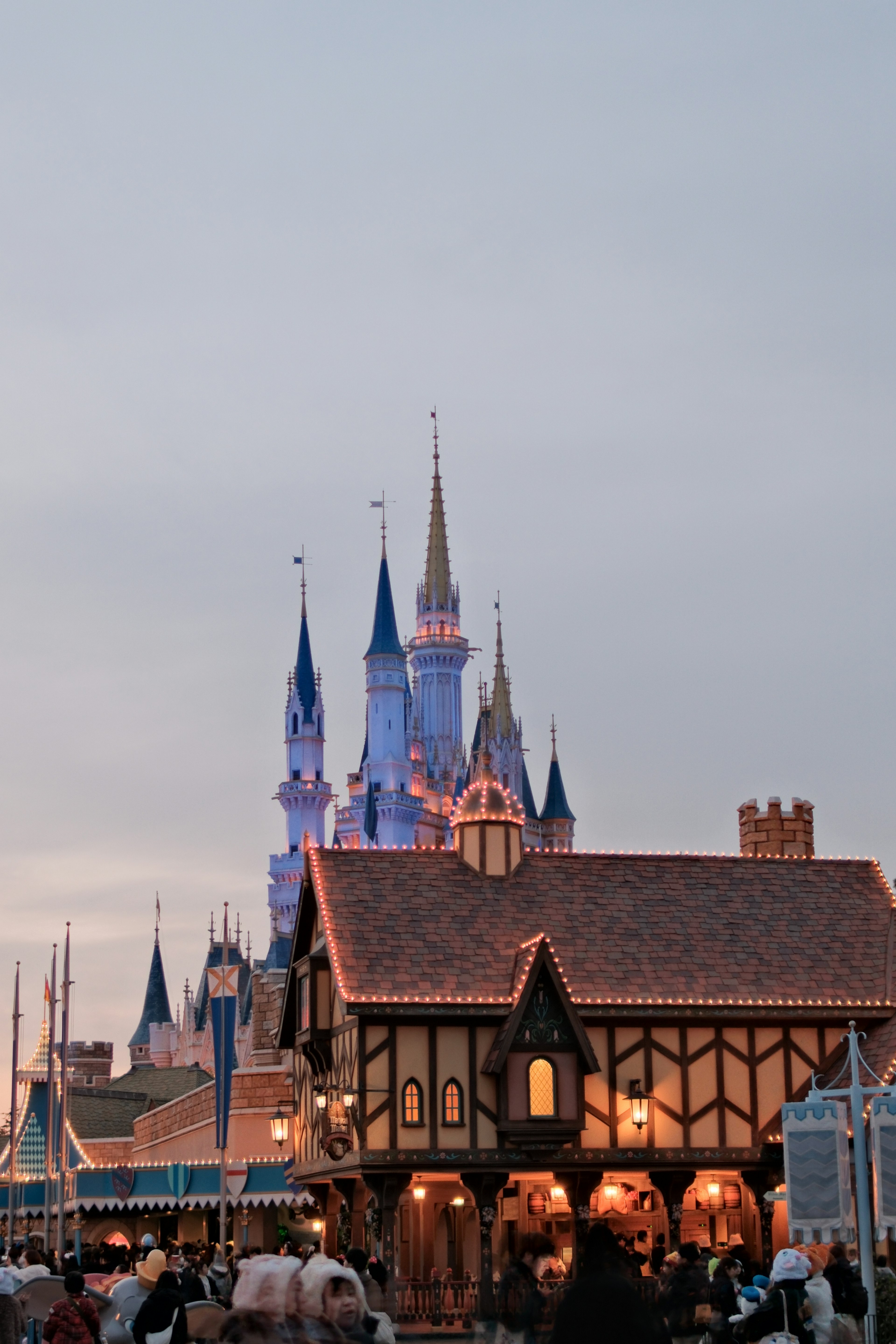 Hermoso castillo de Disney iluminado al anochecer con edificios encantadores en primer plano