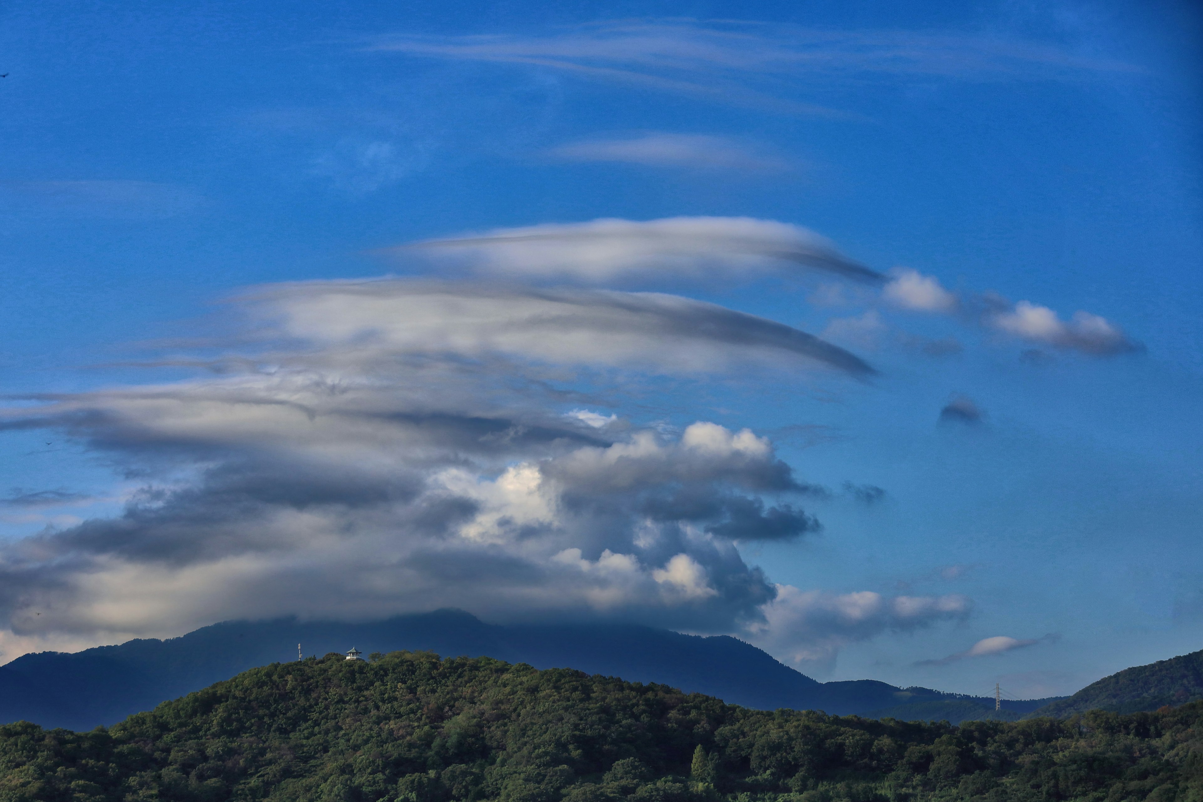 Nuages ondulés dans un ciel bleu au-dessus de montagnes vertes