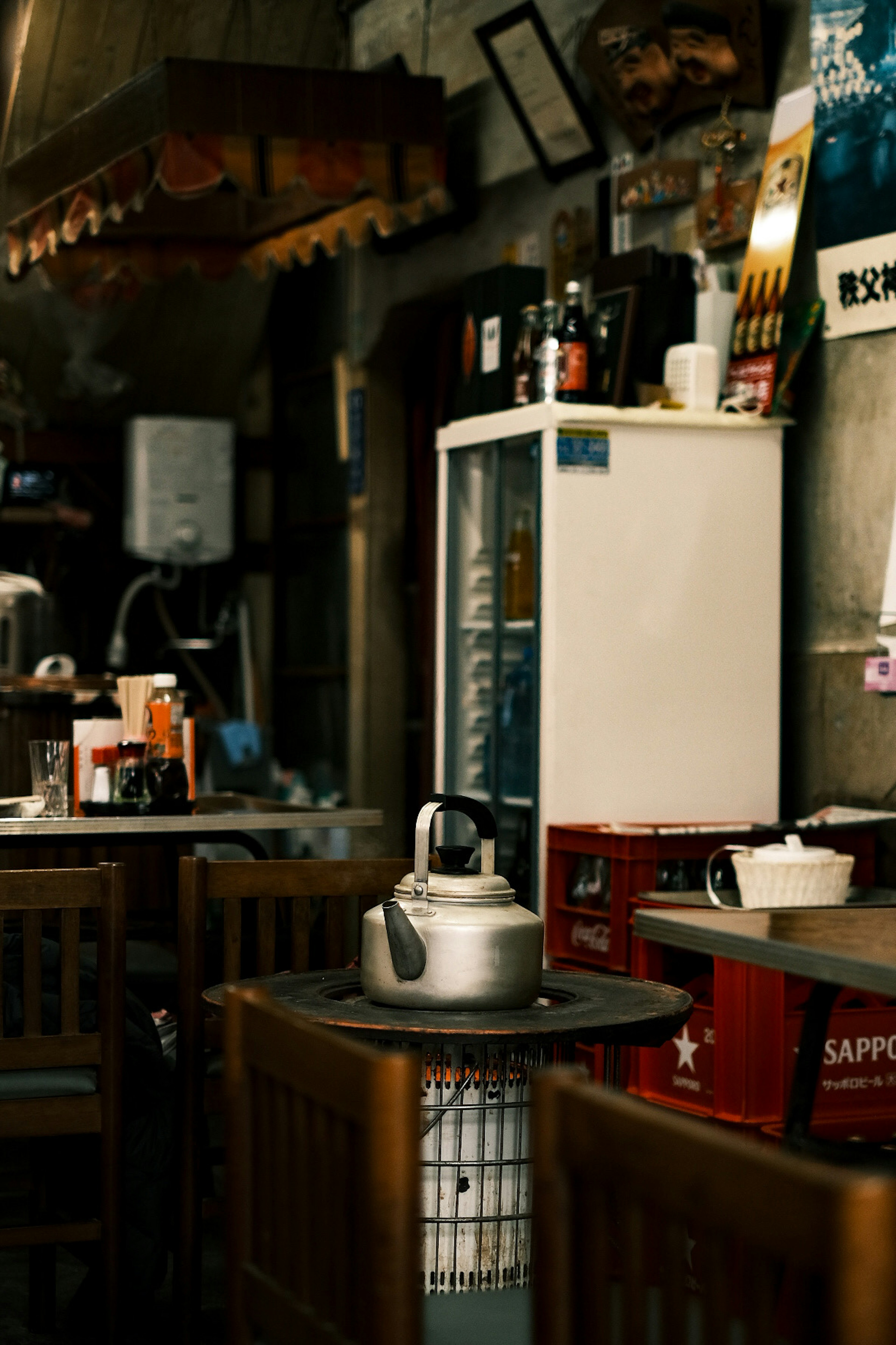 Interior of a cafe with tables and chairs featuring a refrigerator and a kettle