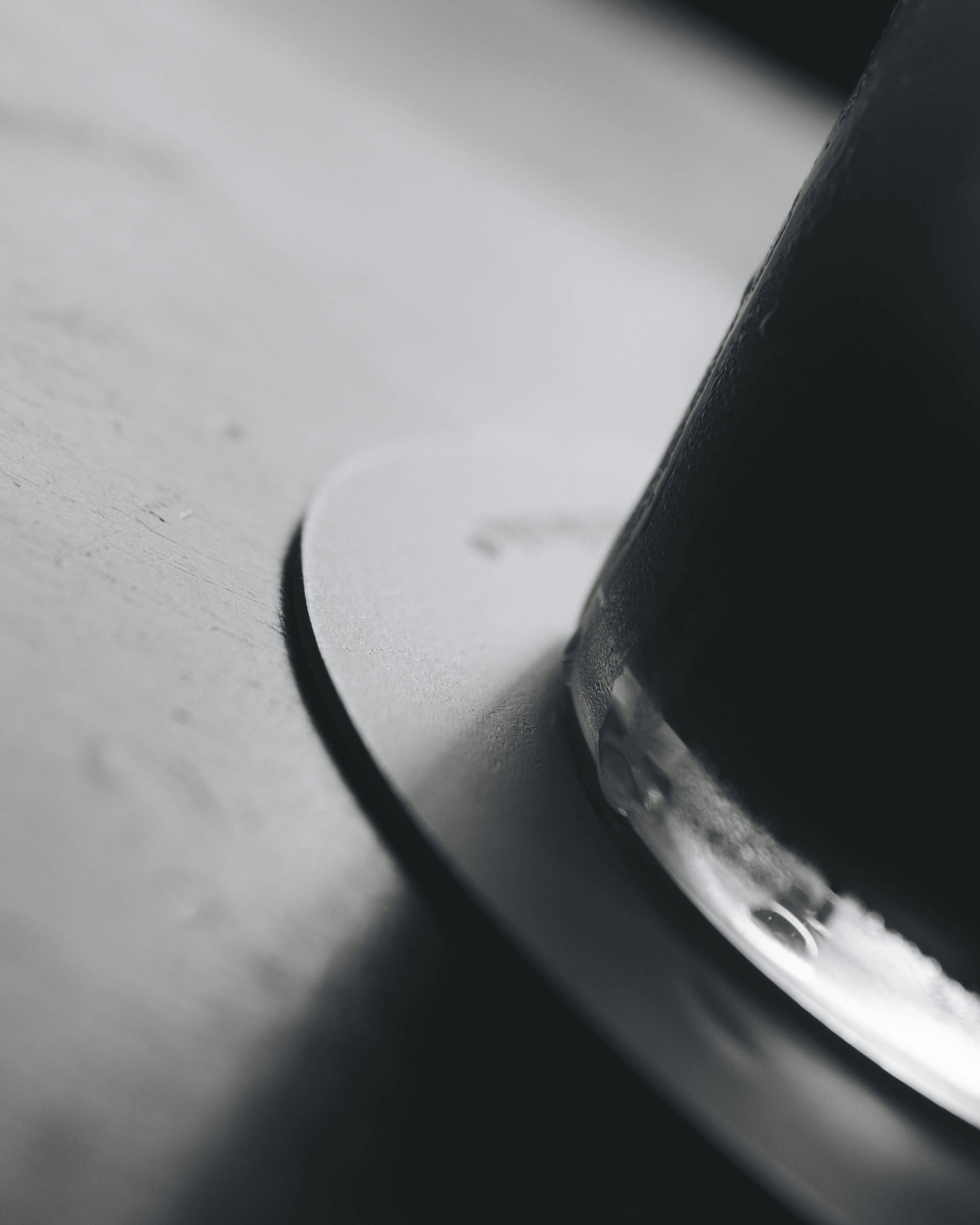 Close-up of a transparent glass on a dark surface with a circular coaster