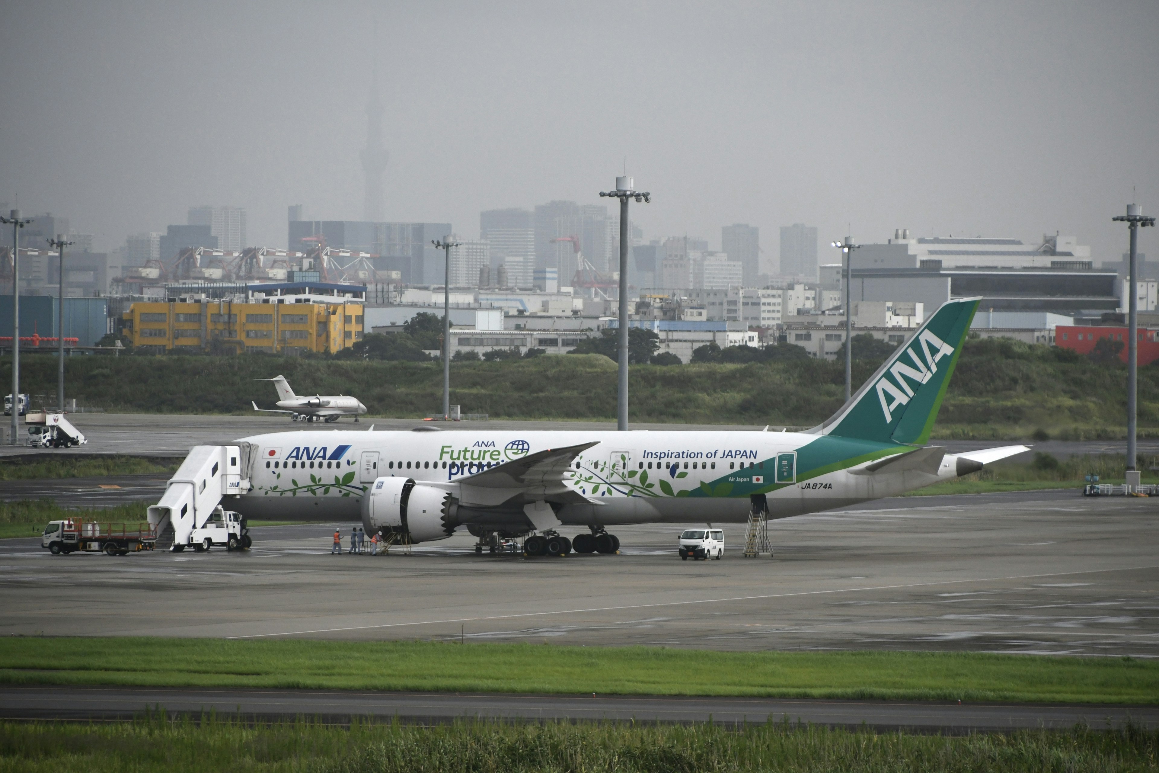 ANA飛機停在機場，背景是城市天際線