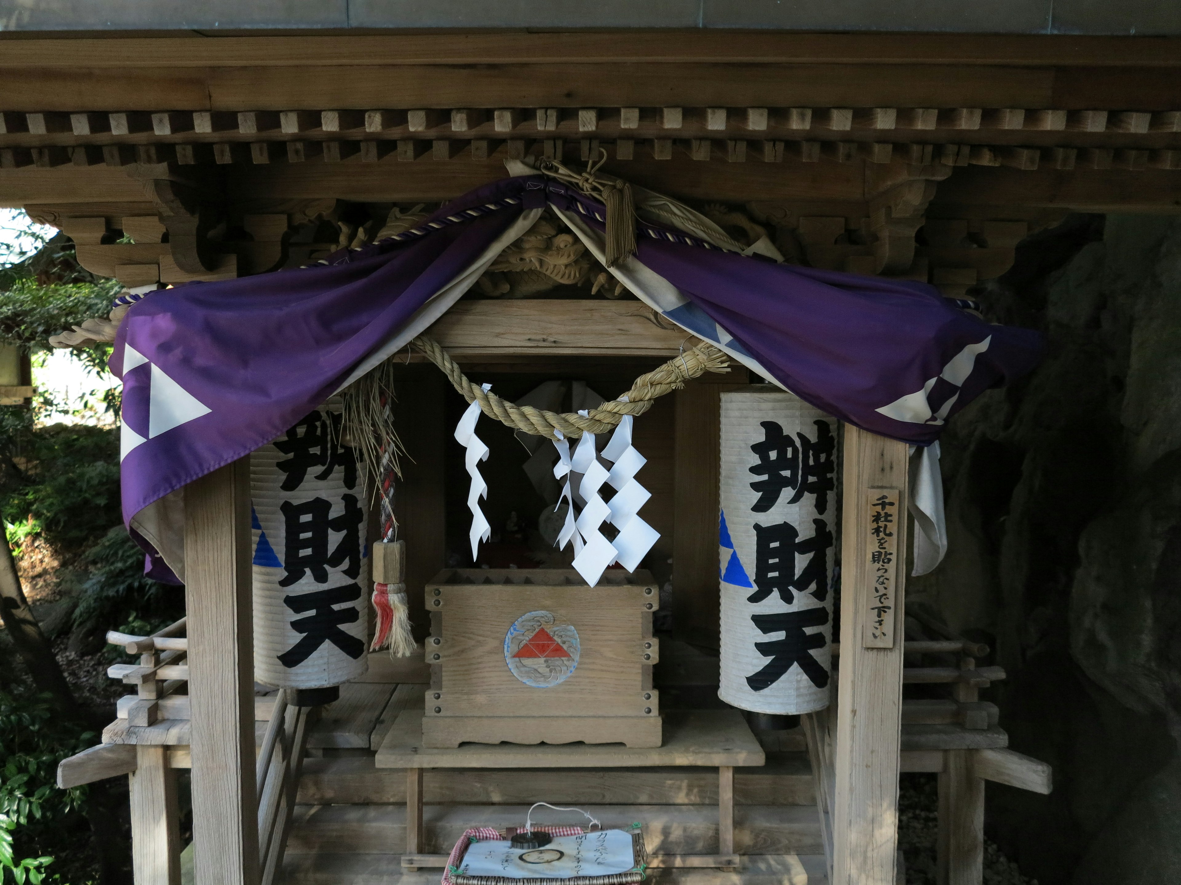 小さな神社の建物に紫色の幕がかかっている