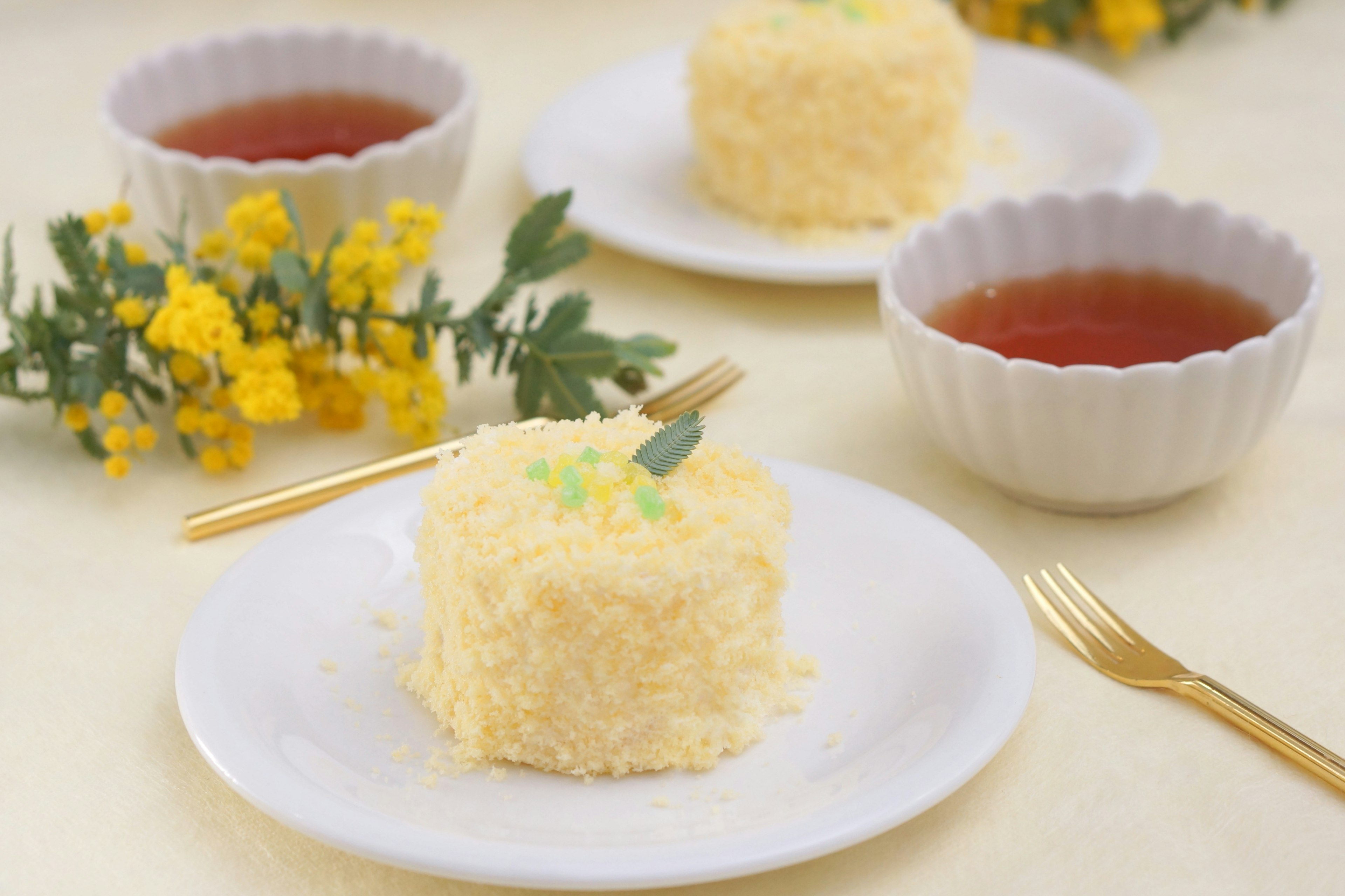 Fluffiger Kuchen serviert mit gelben Blumen und Tee