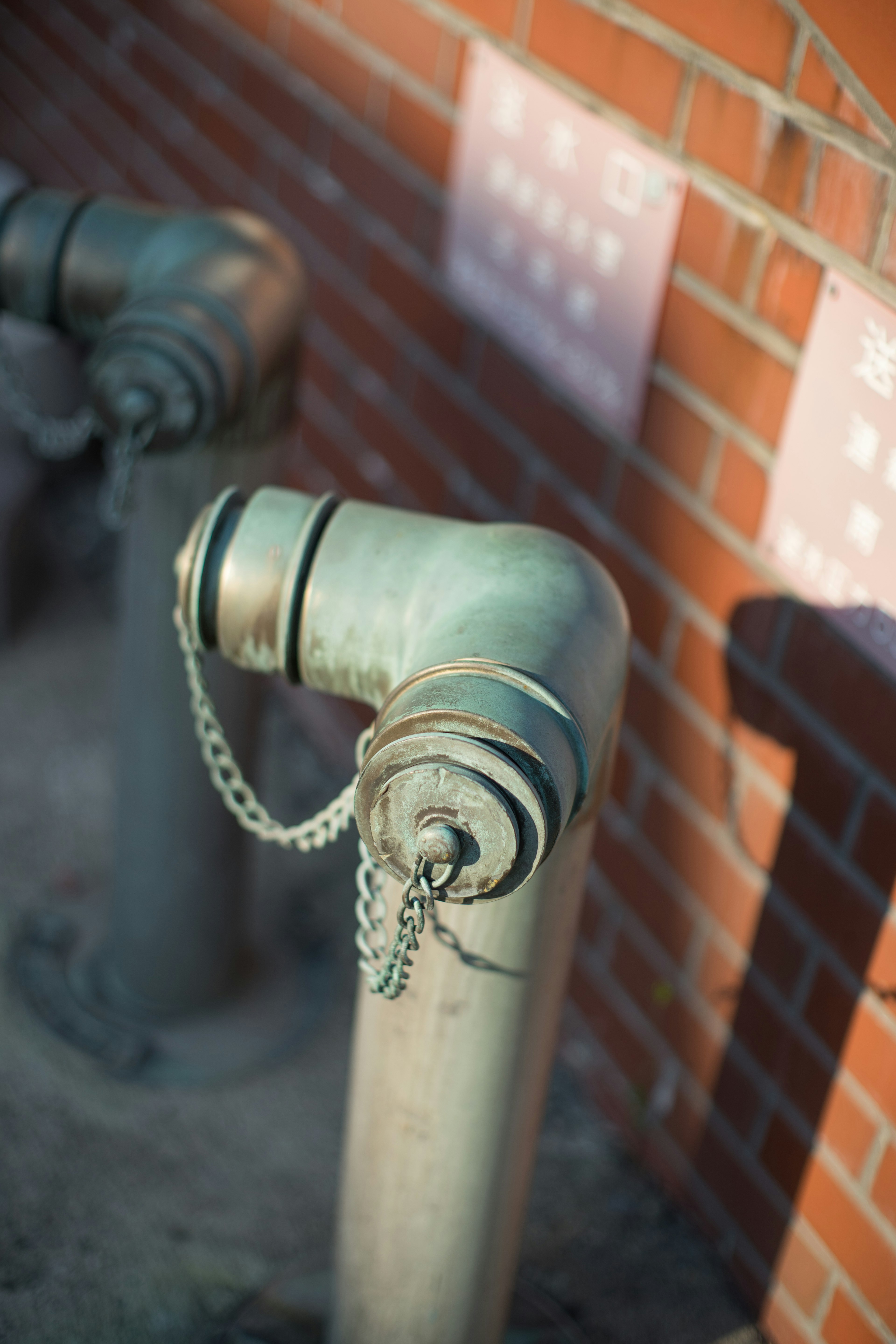 Close-up of a metal pipe fitting attached to a red brick wall