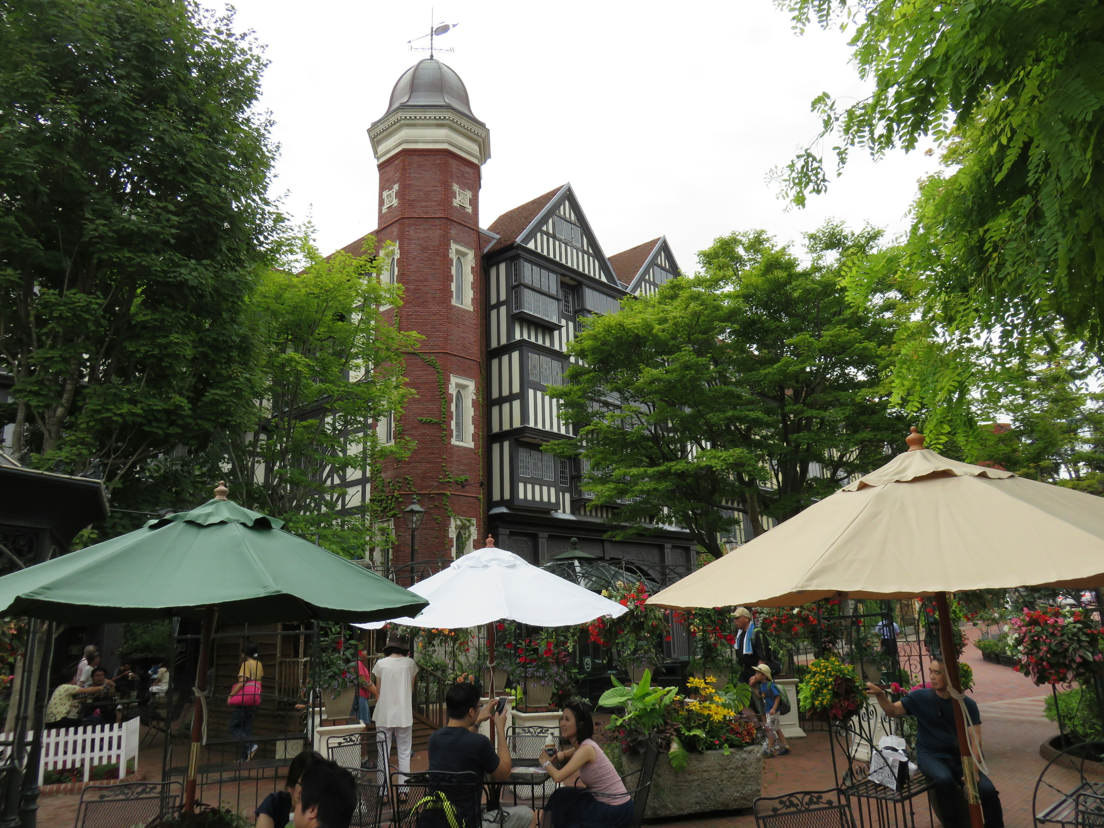 Caféterrasse umgeben von üppigem Grün und einem historischen Gebäude