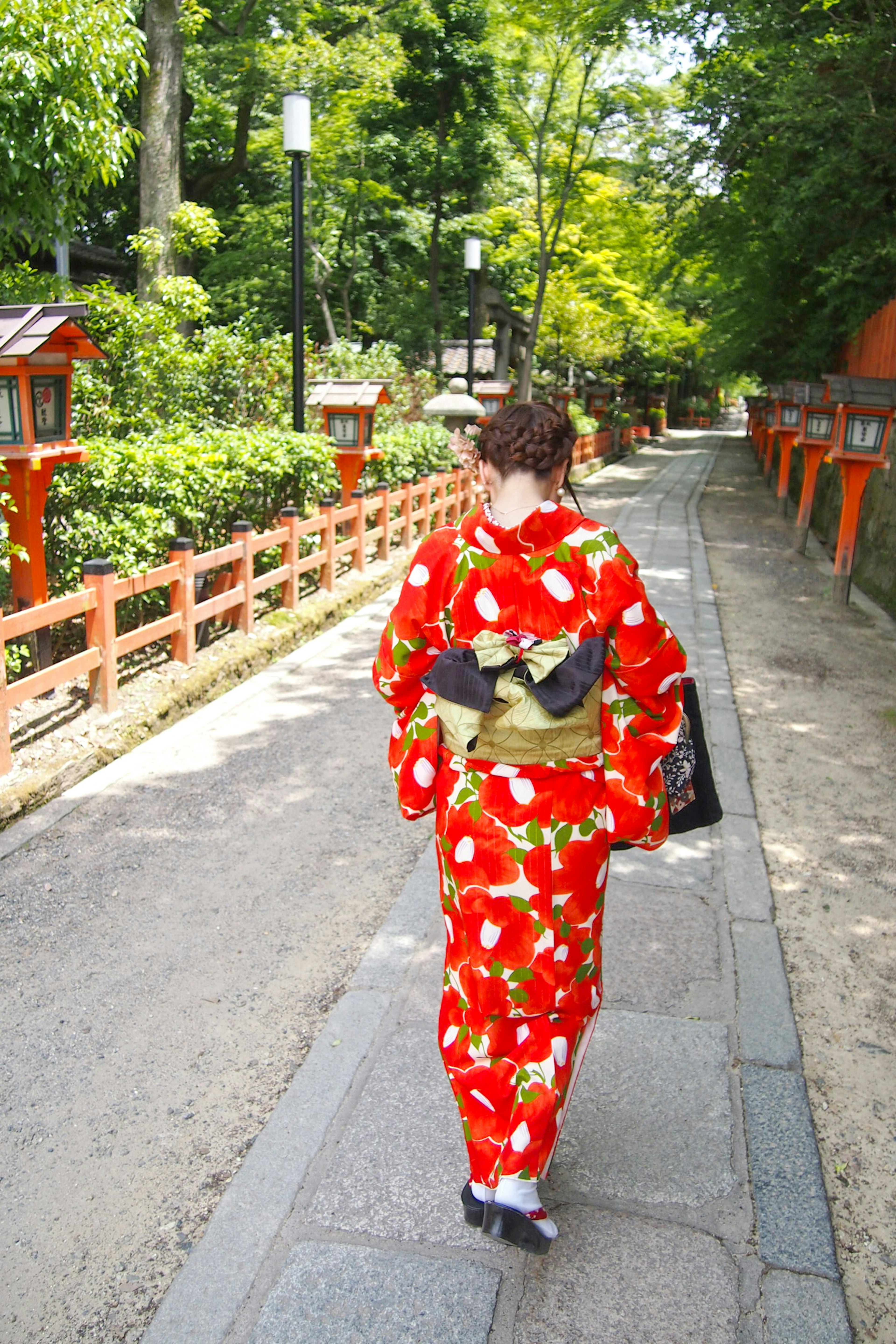 Femme en kimono floral rouge marchant le long d'un chemin