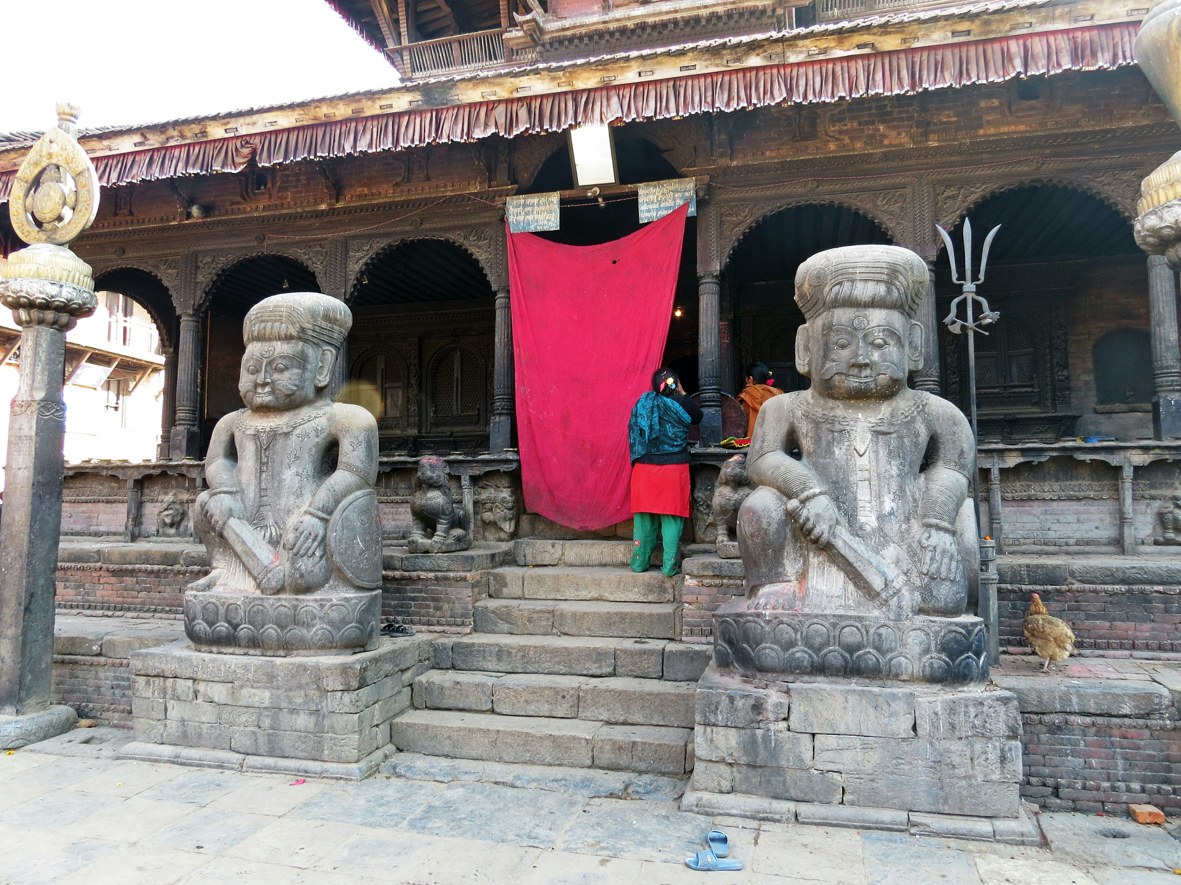 Dos estatuas de piedra en la entrada de un templo con una cortina roja