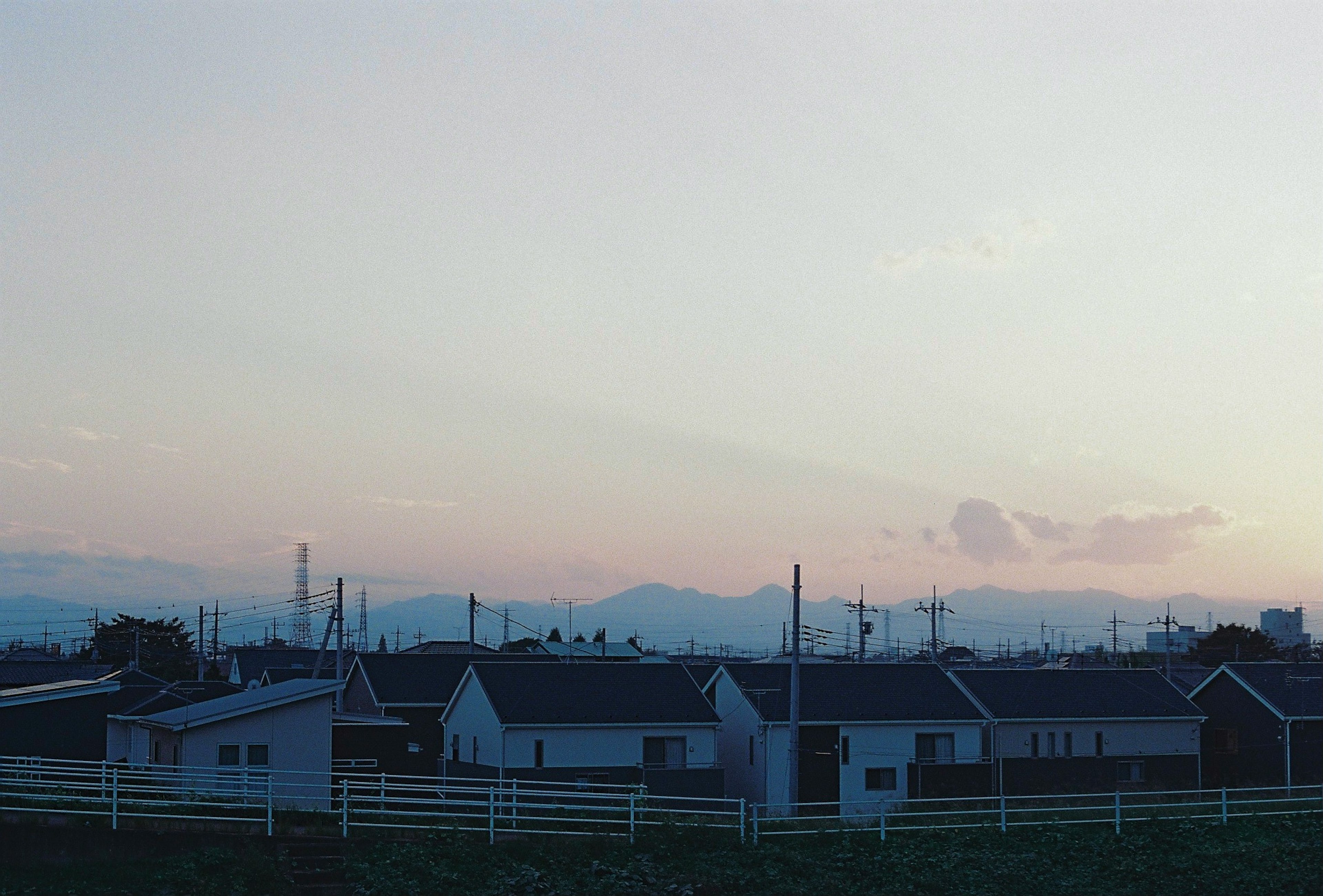 夕暮れ時の住宅街と遠くの山々を背景にした風景