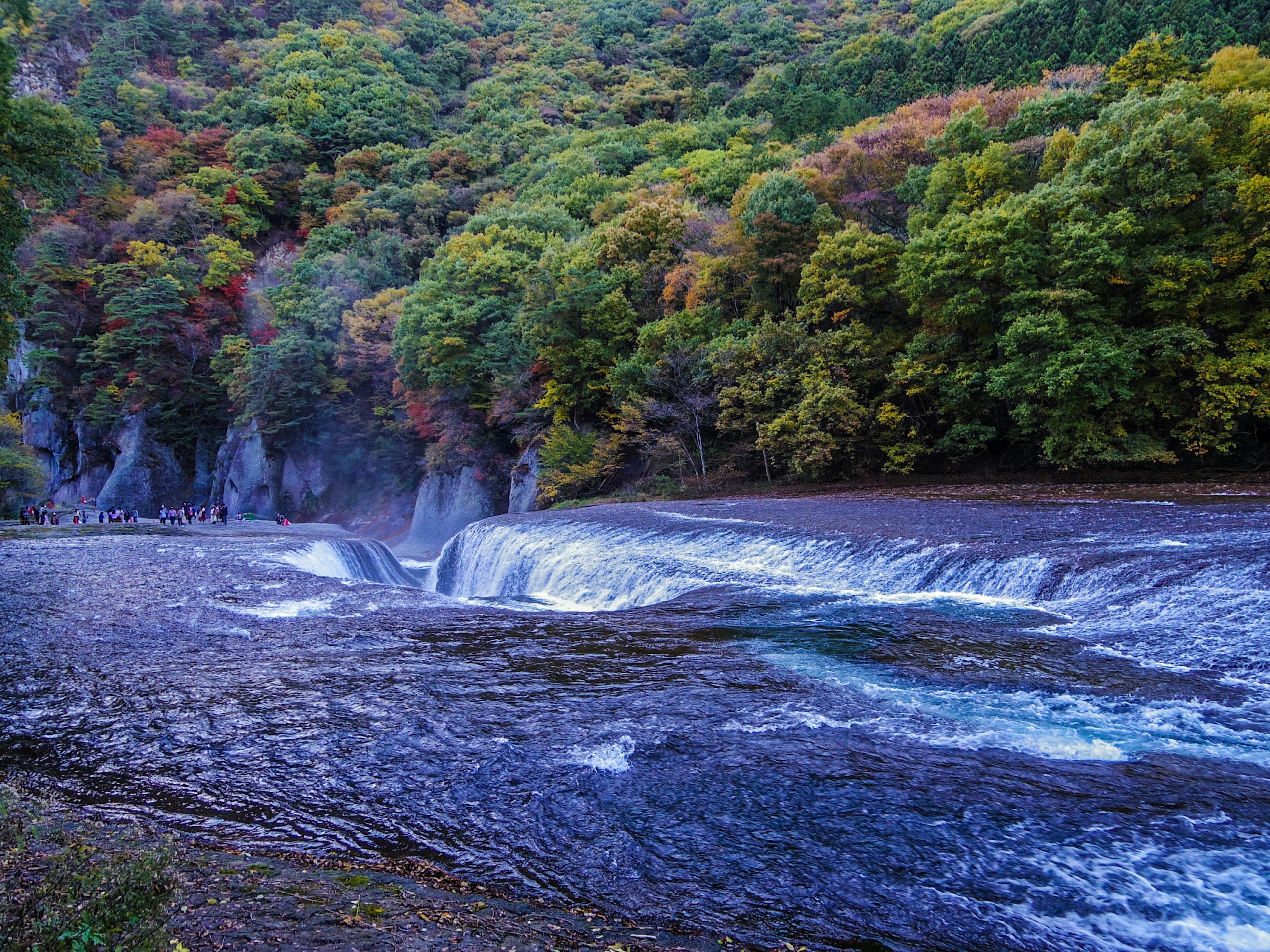 Una scena di cascata serena circondata da foglie autunnali colorate