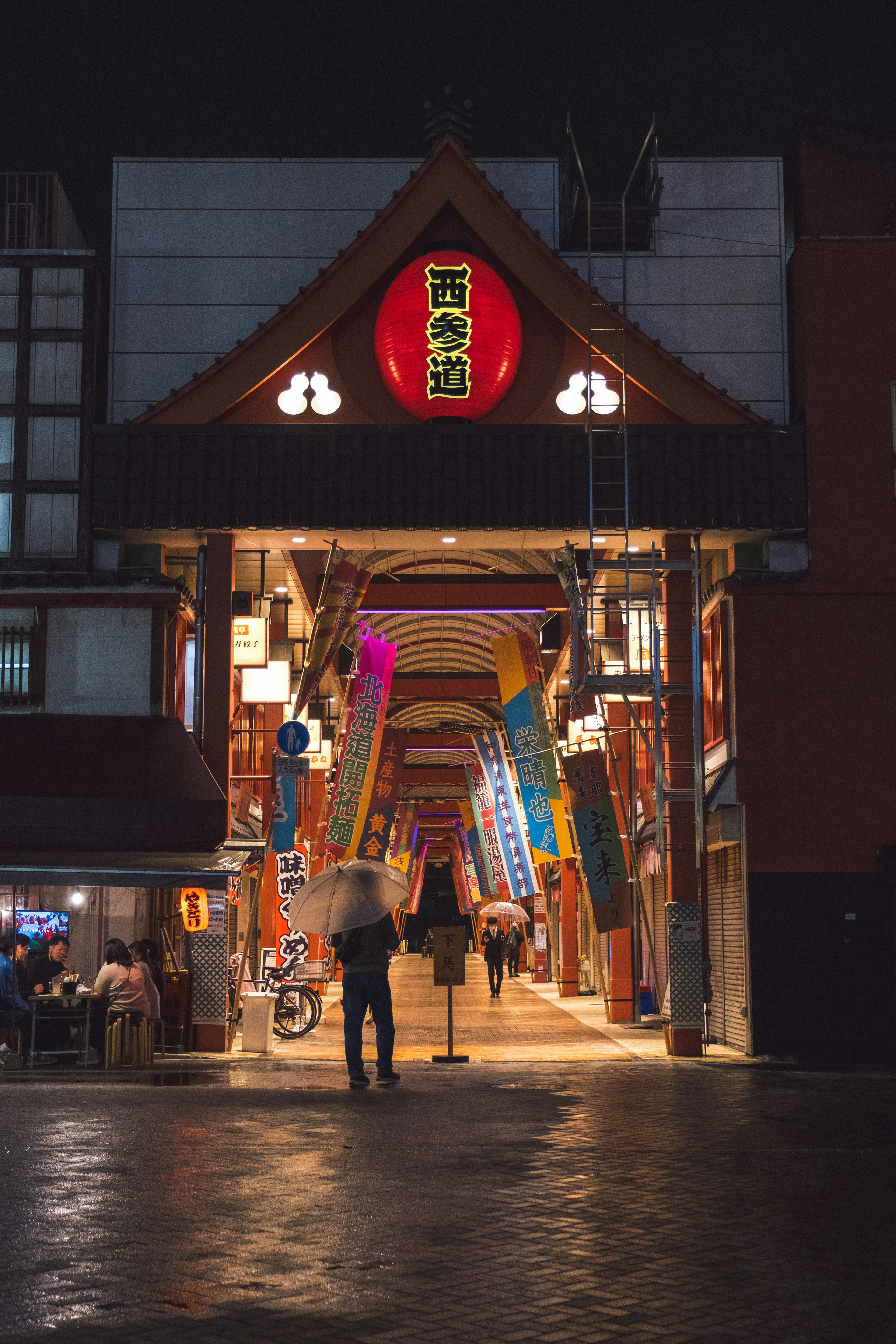 ทางเข้าถนนช้อปปิ้งในตอนกลางคืนพร้อมป้ายสีแดงและไฟสว่าง