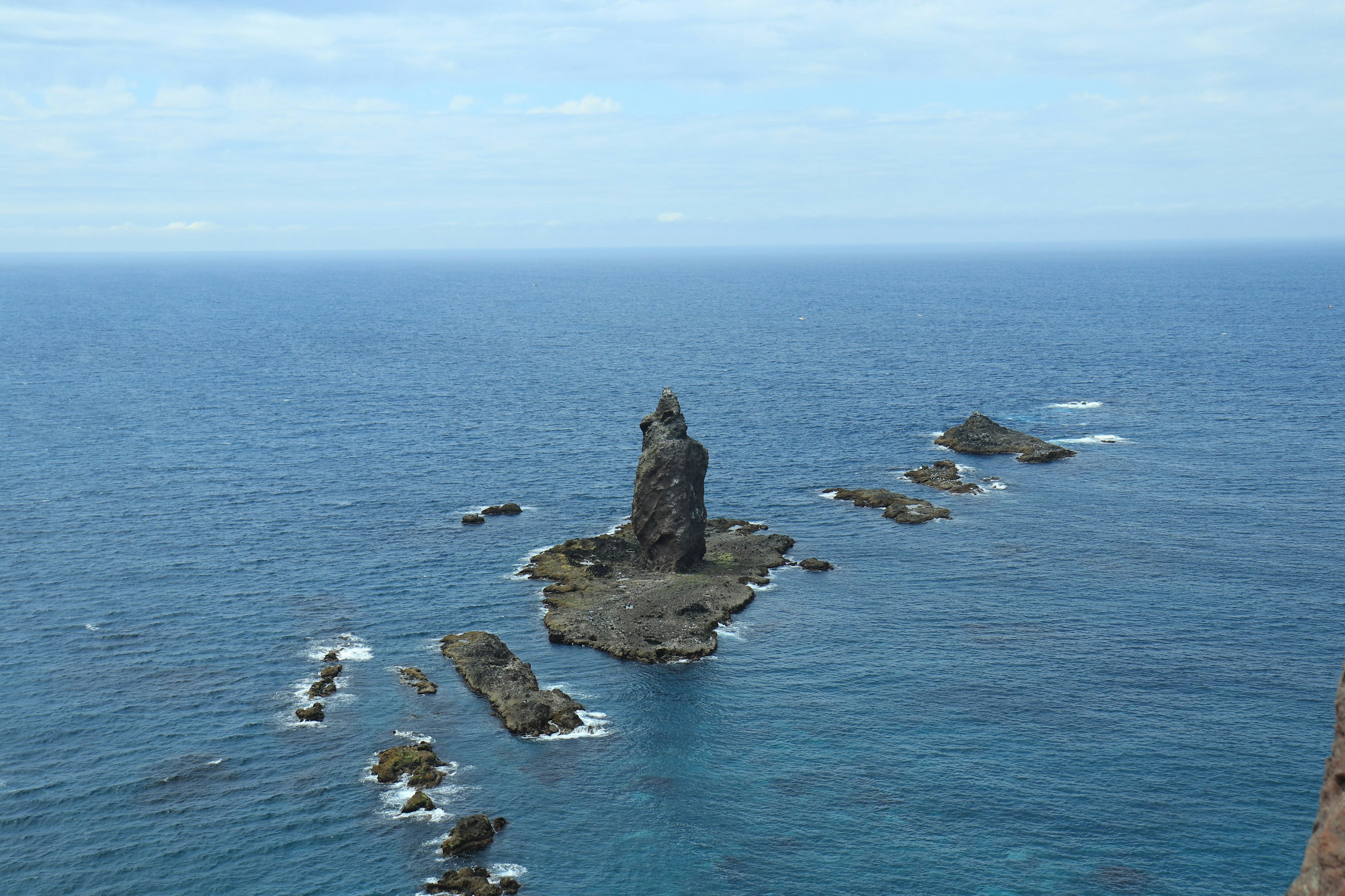 Island rock formation in the ocean under a blue sky