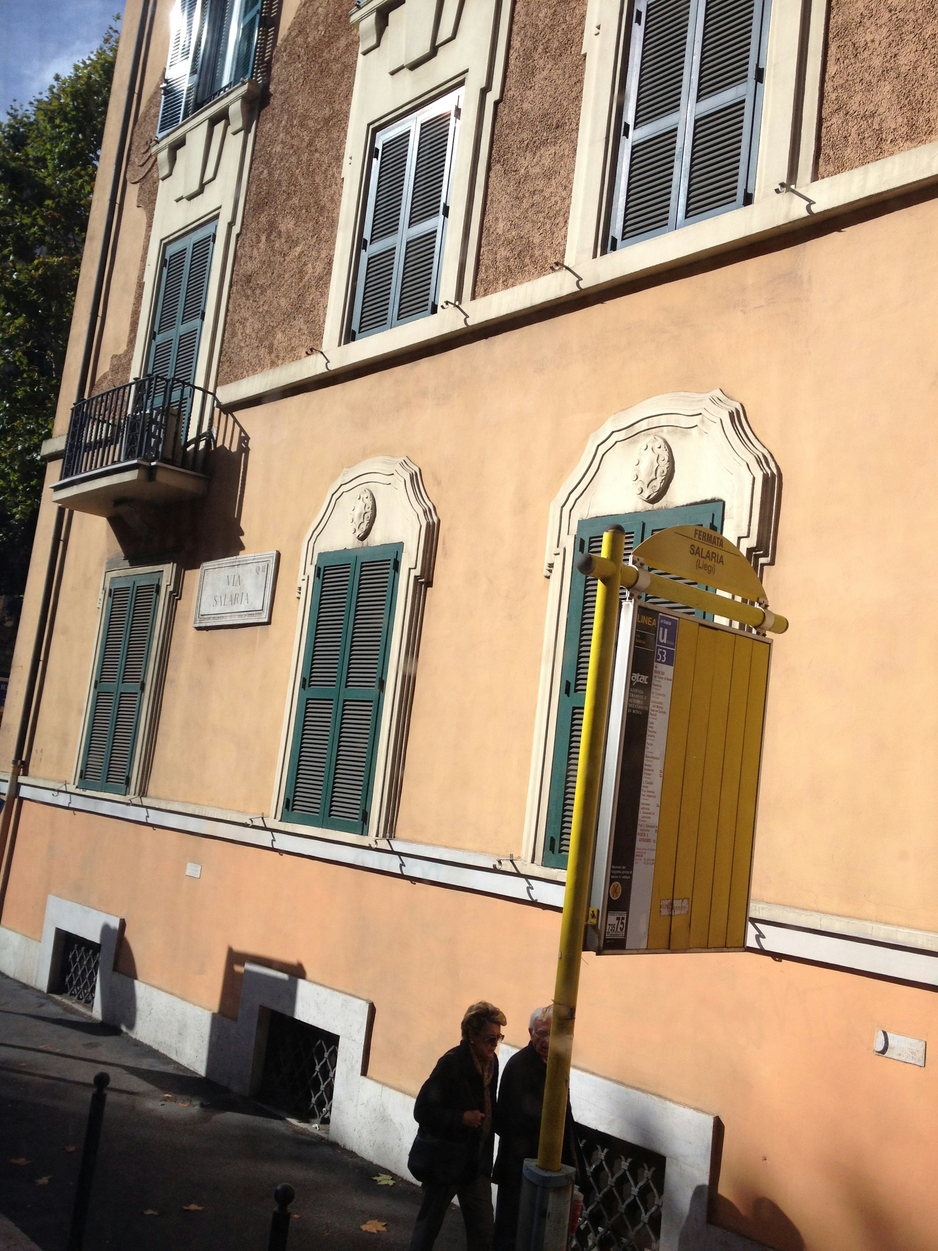 Lado de un edificio con exterior naranja y ventanas verdes