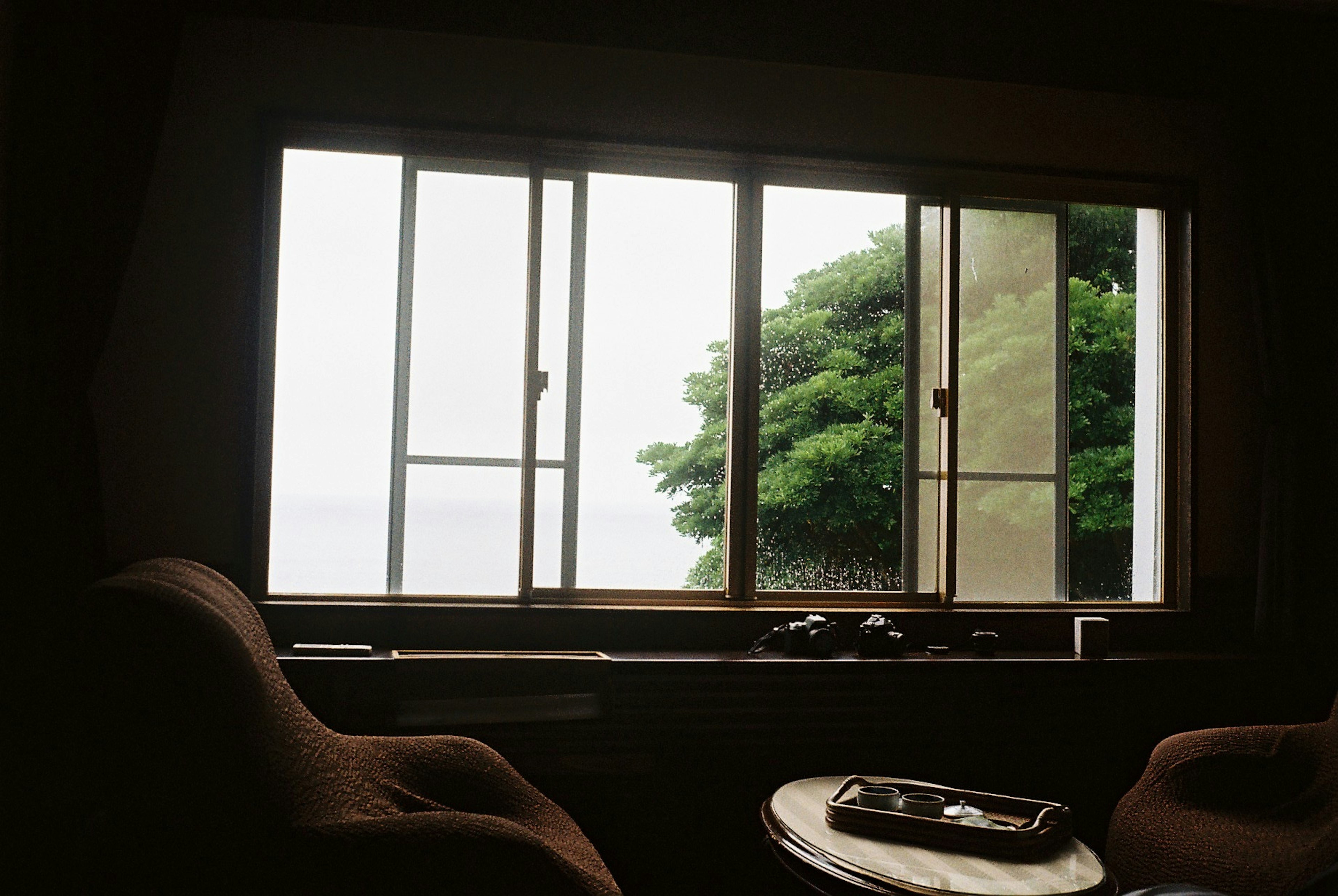 Interior view of a room with a window showing greenery and the sea