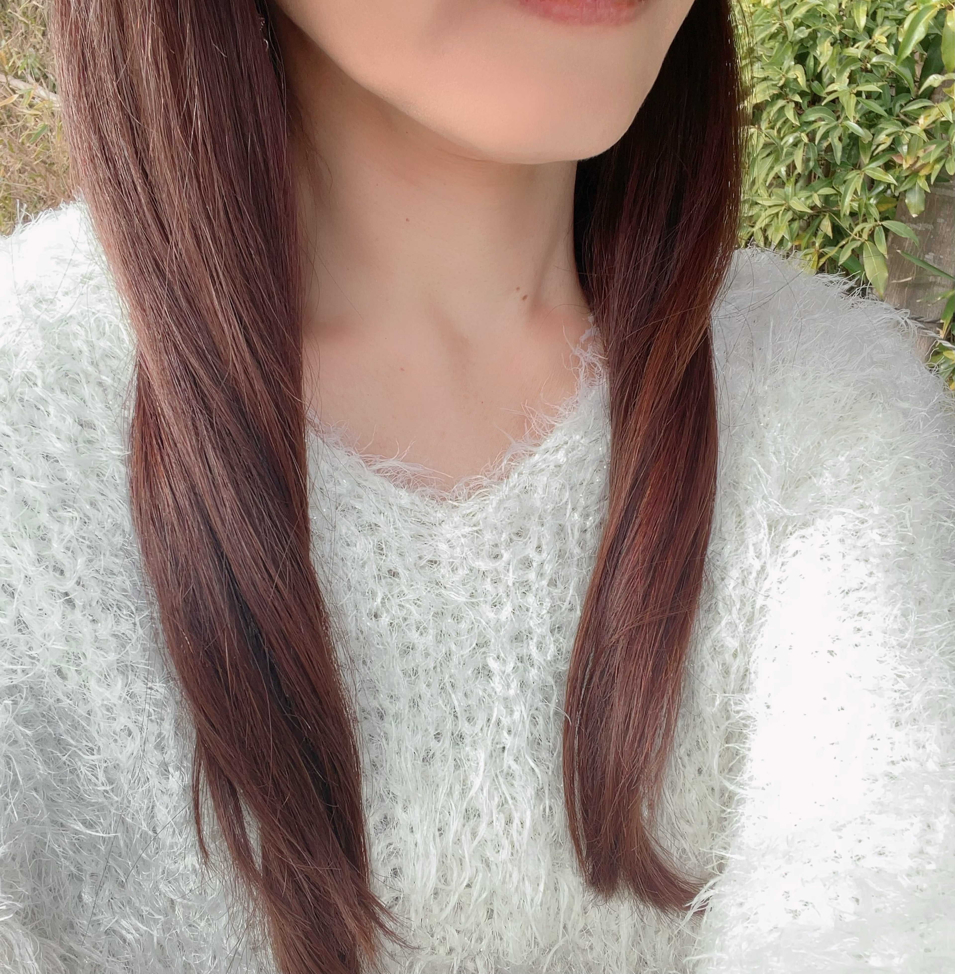 Close-up of a woman wearing a fluffy white sweater with long brown hair