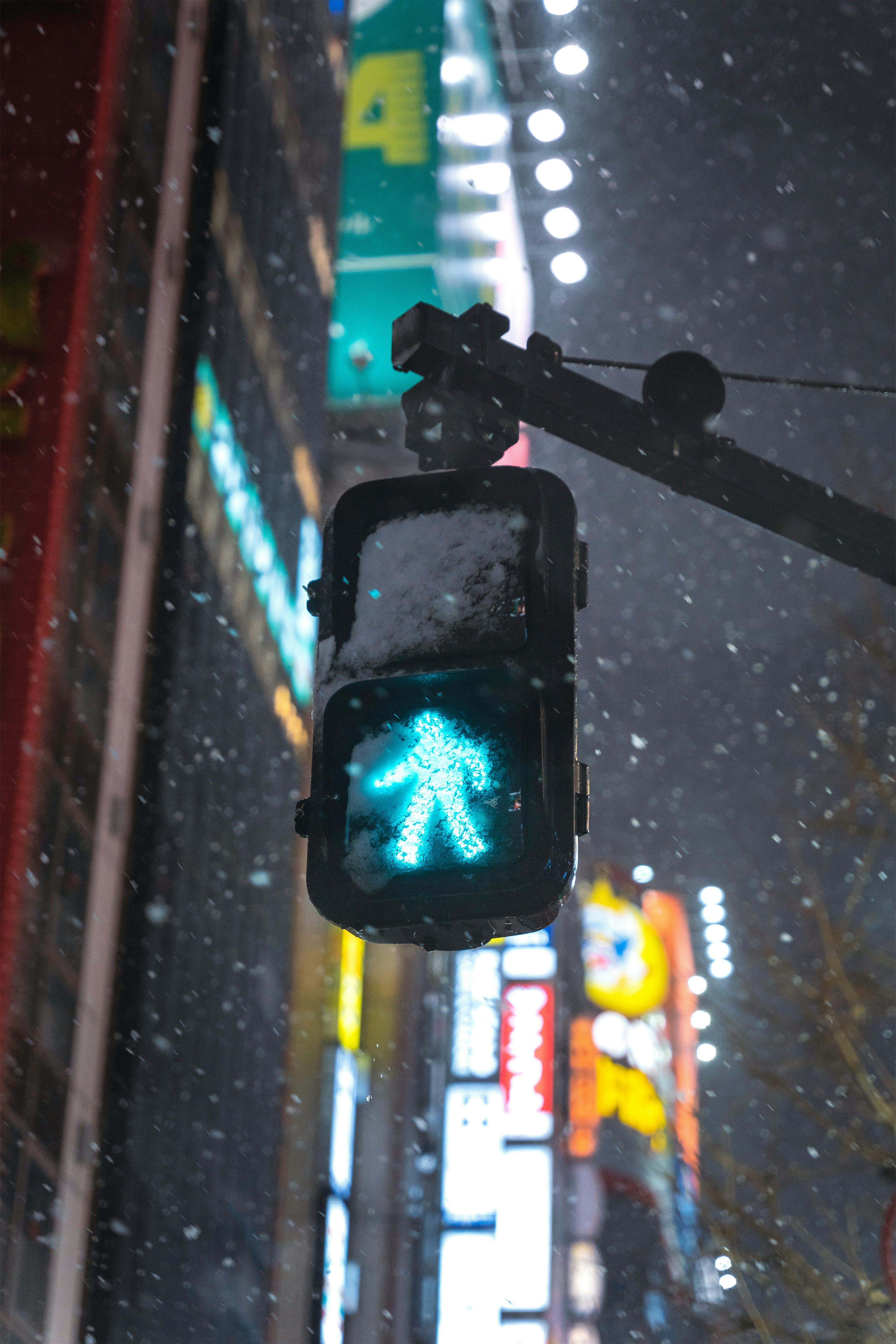 Green pedestrian signal illuminated in snowy night cityscape