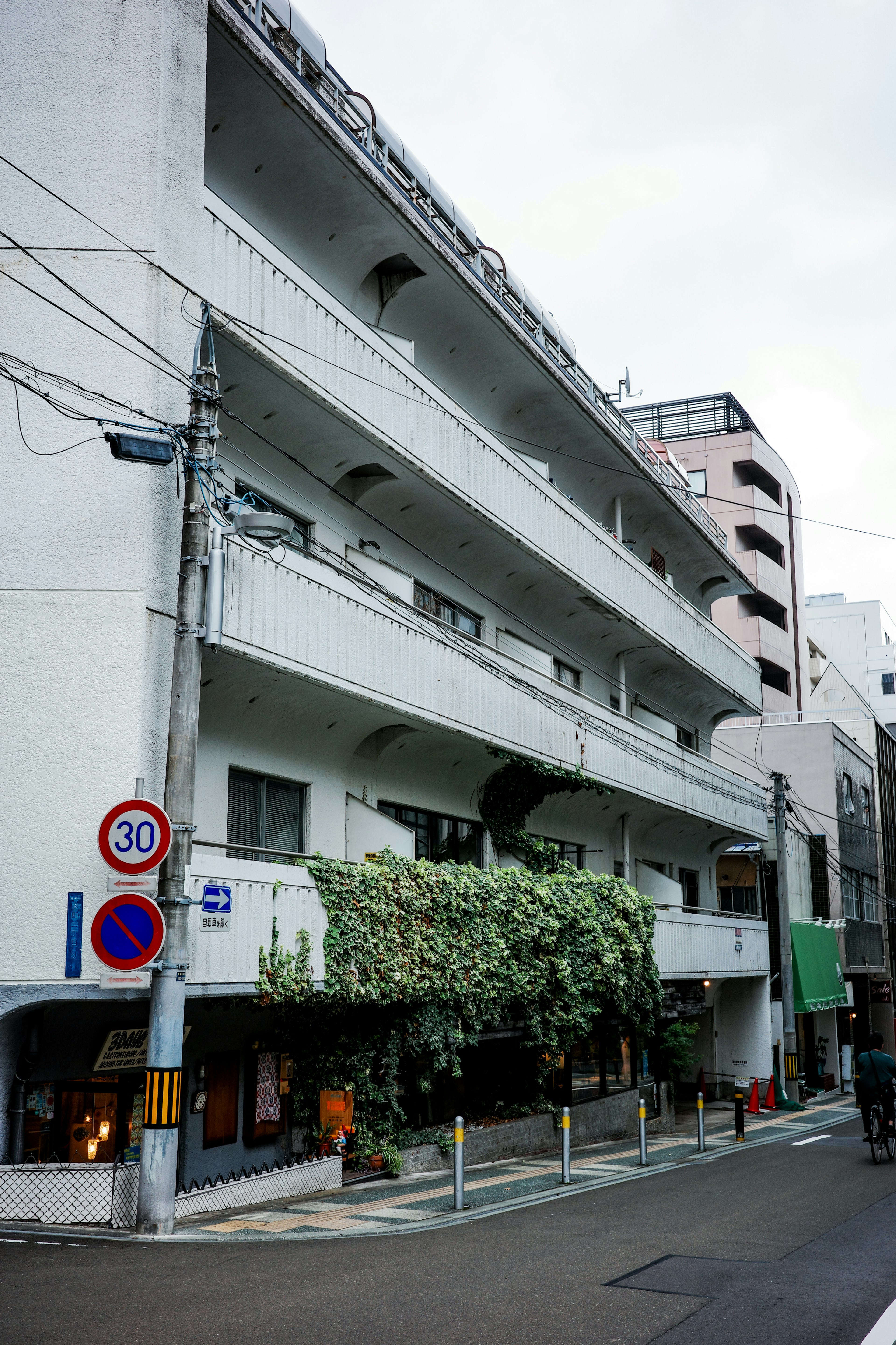 Street view featuring a four-story apartment building with a white facade