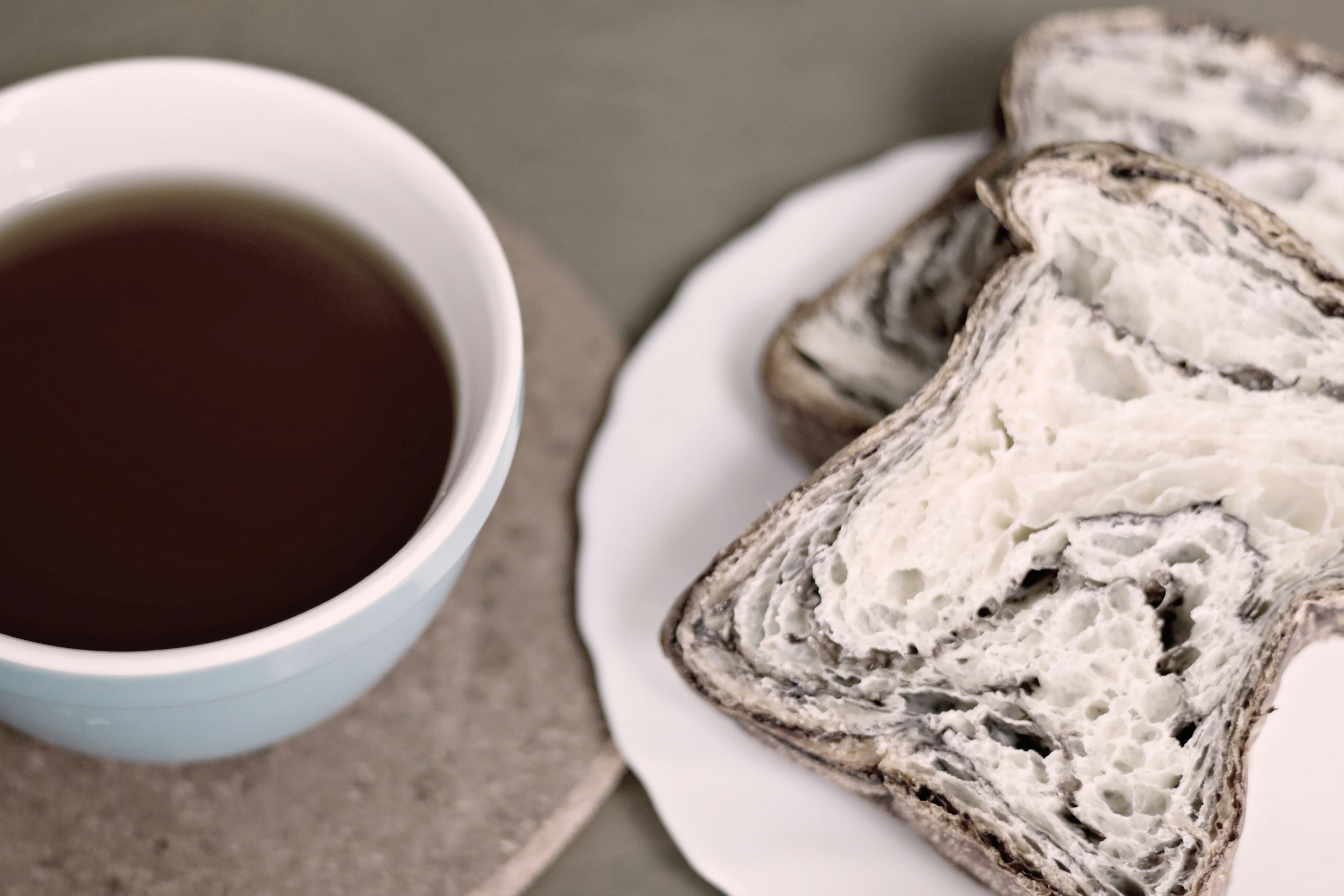 Marble-patterned black and white bread with a cup of dark beverage on a simple table setting