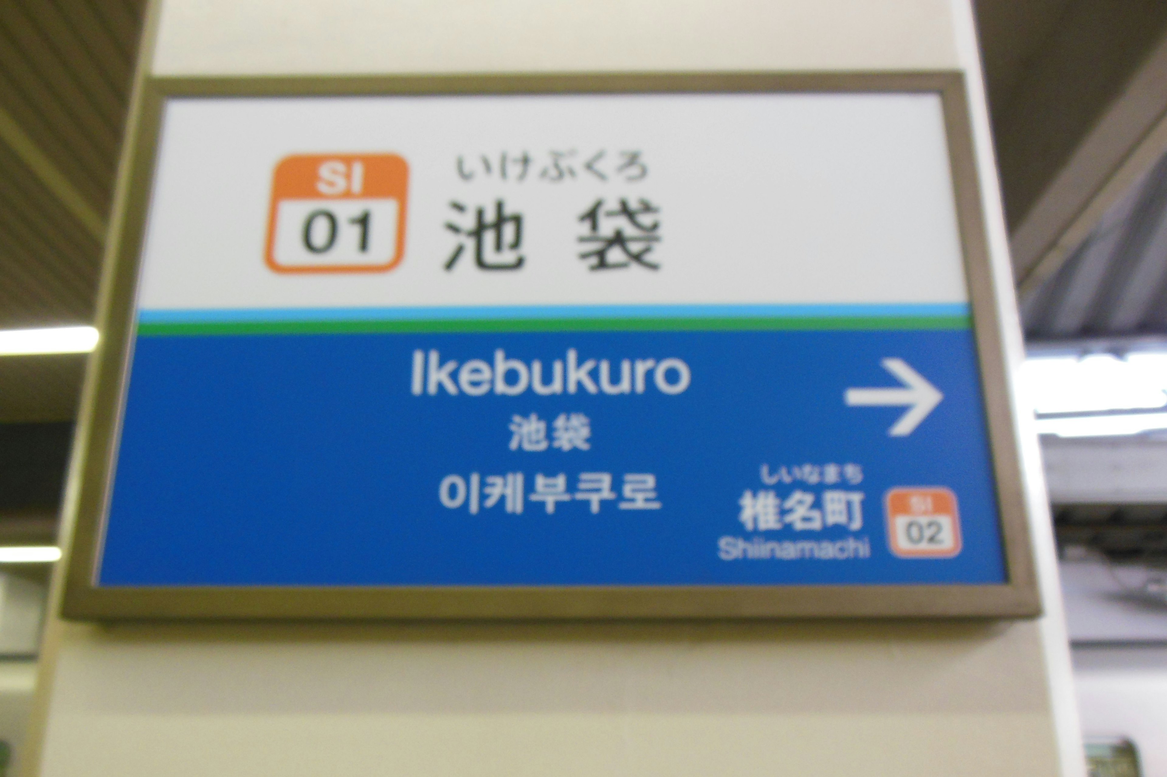 Tanda untuk Stasiun Ikebukuro dengan latar belakang biru dan teks putih