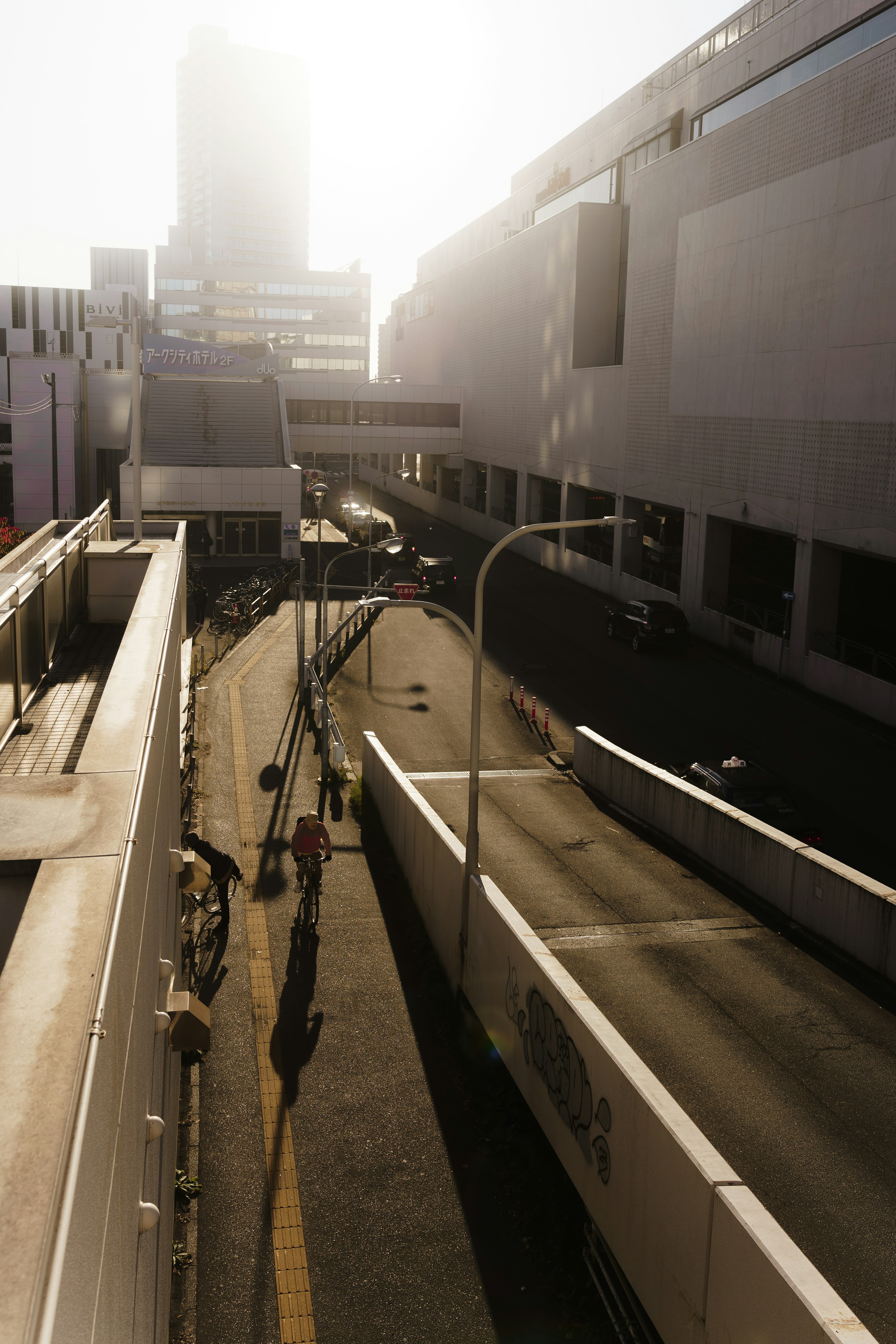 Photo of a road between skyscrapers with strong sunlight