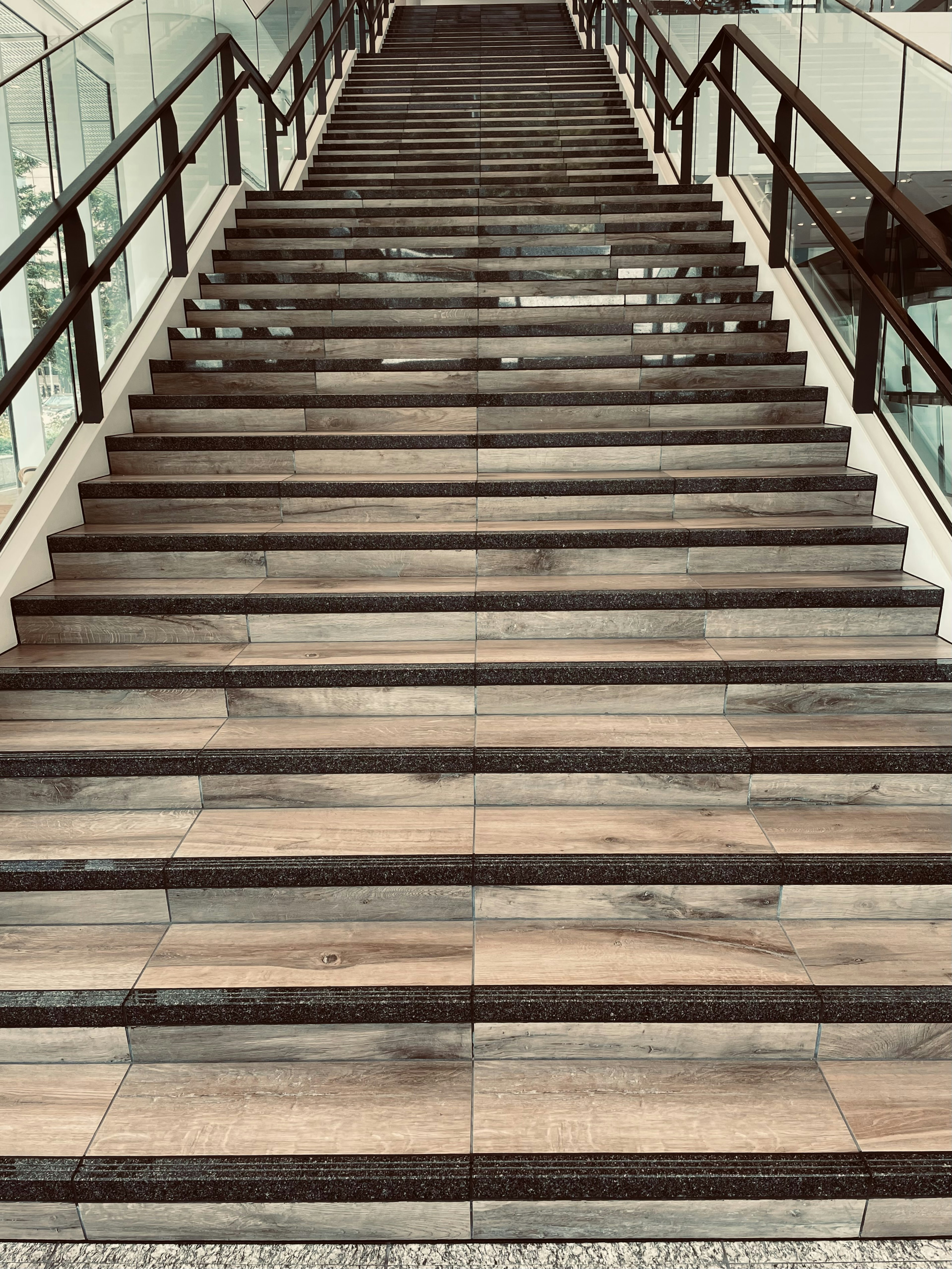 View from the top of a modern staircase featuring wood-patterned tiles