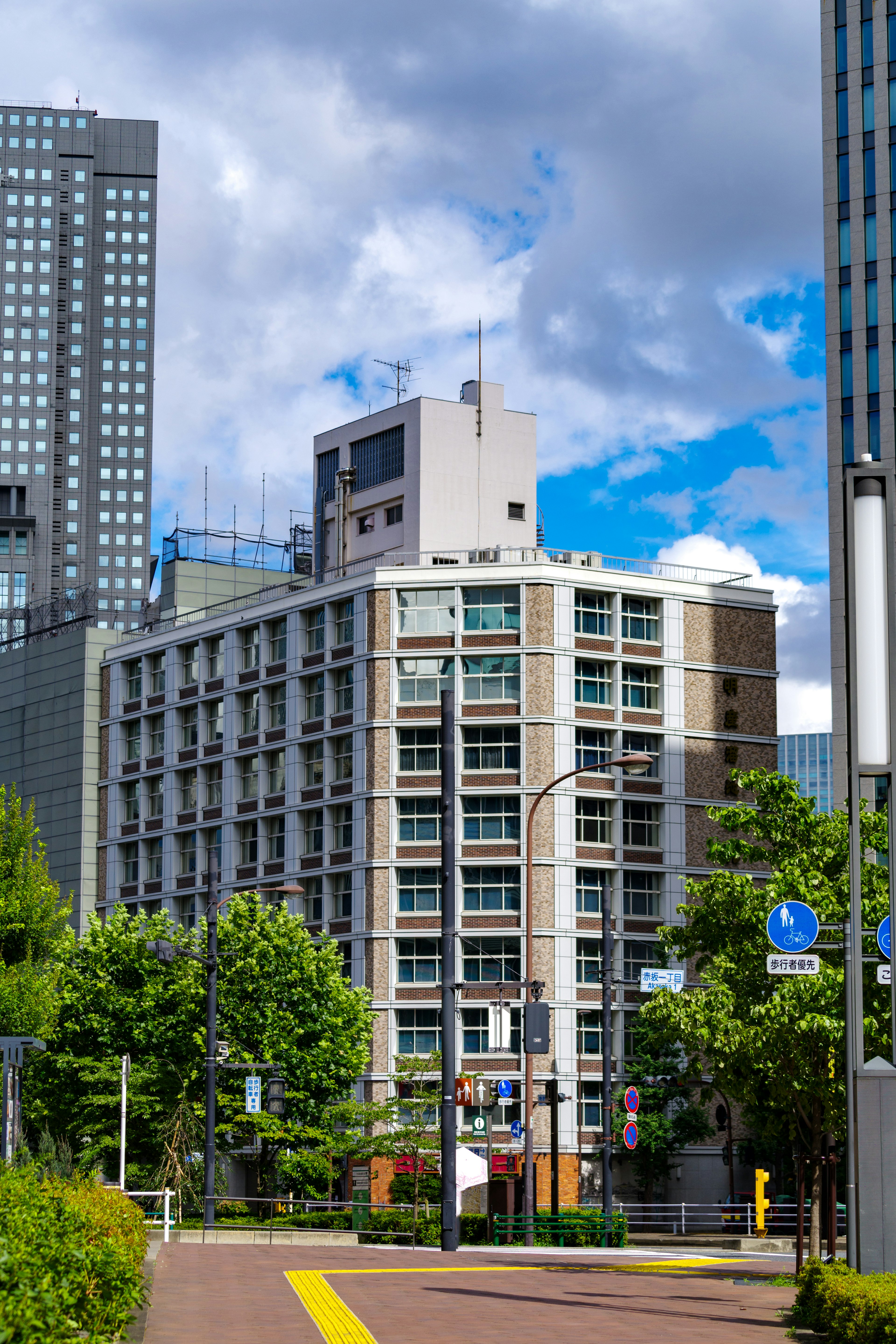 Un immeuble de bureaux entouré de gratte-ciels avec une verdure luxuriante et un ciel bleu