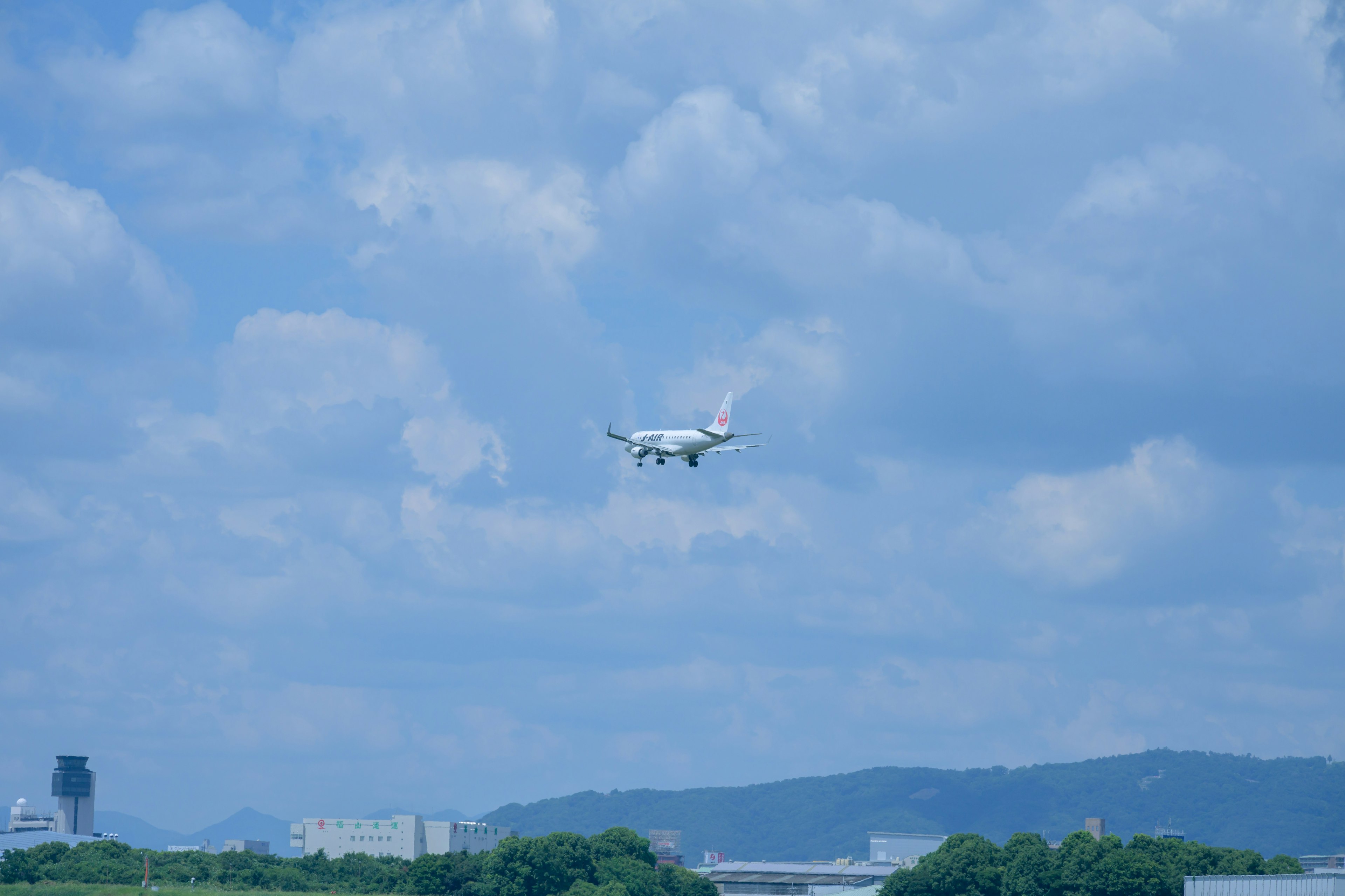 Un aereo che vola sotto un cielo blu con nuvole sparse