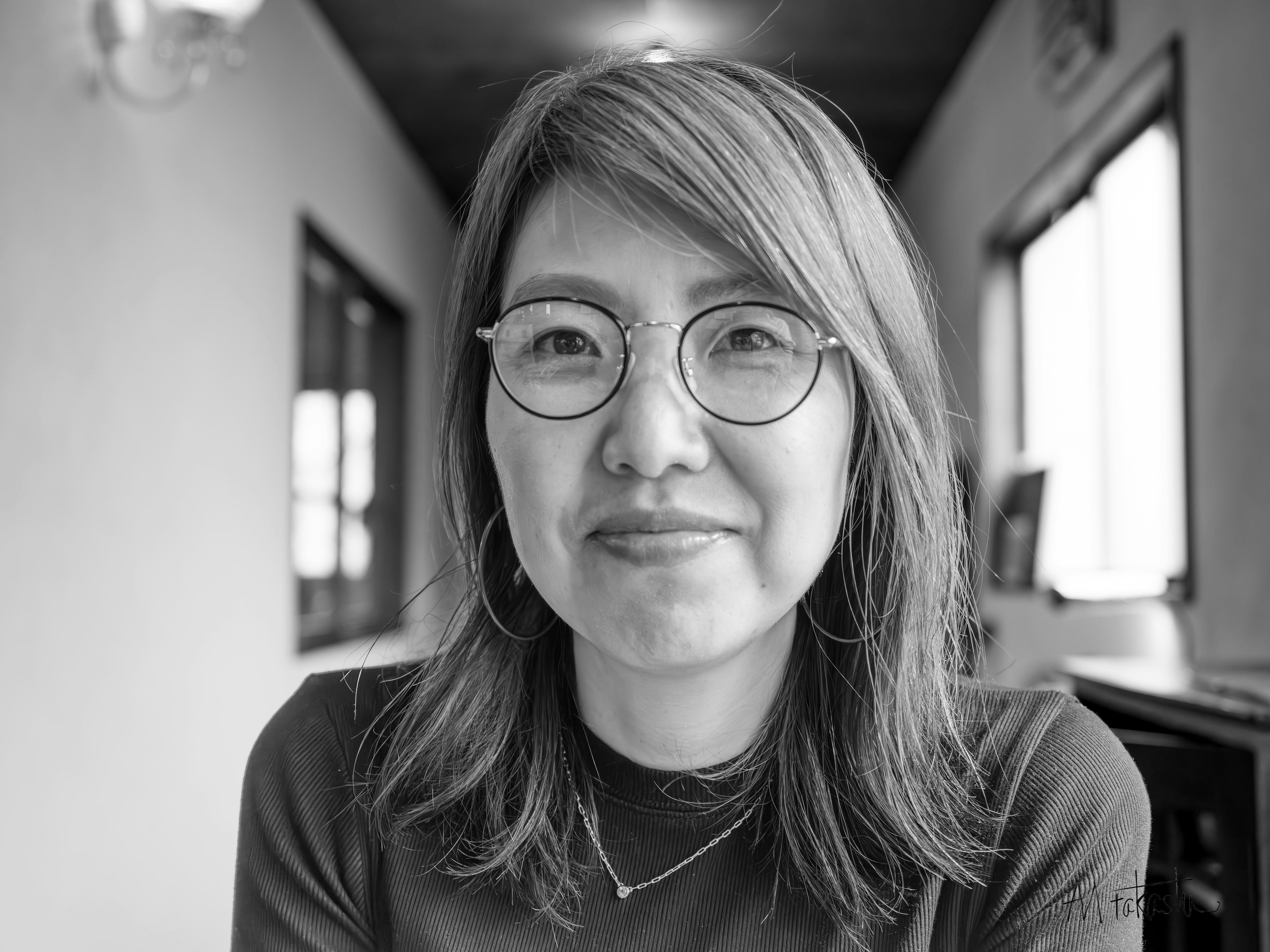 Retrato en blanco y negro de una mujer sonriente con cabello hasta los hombros usando gafas