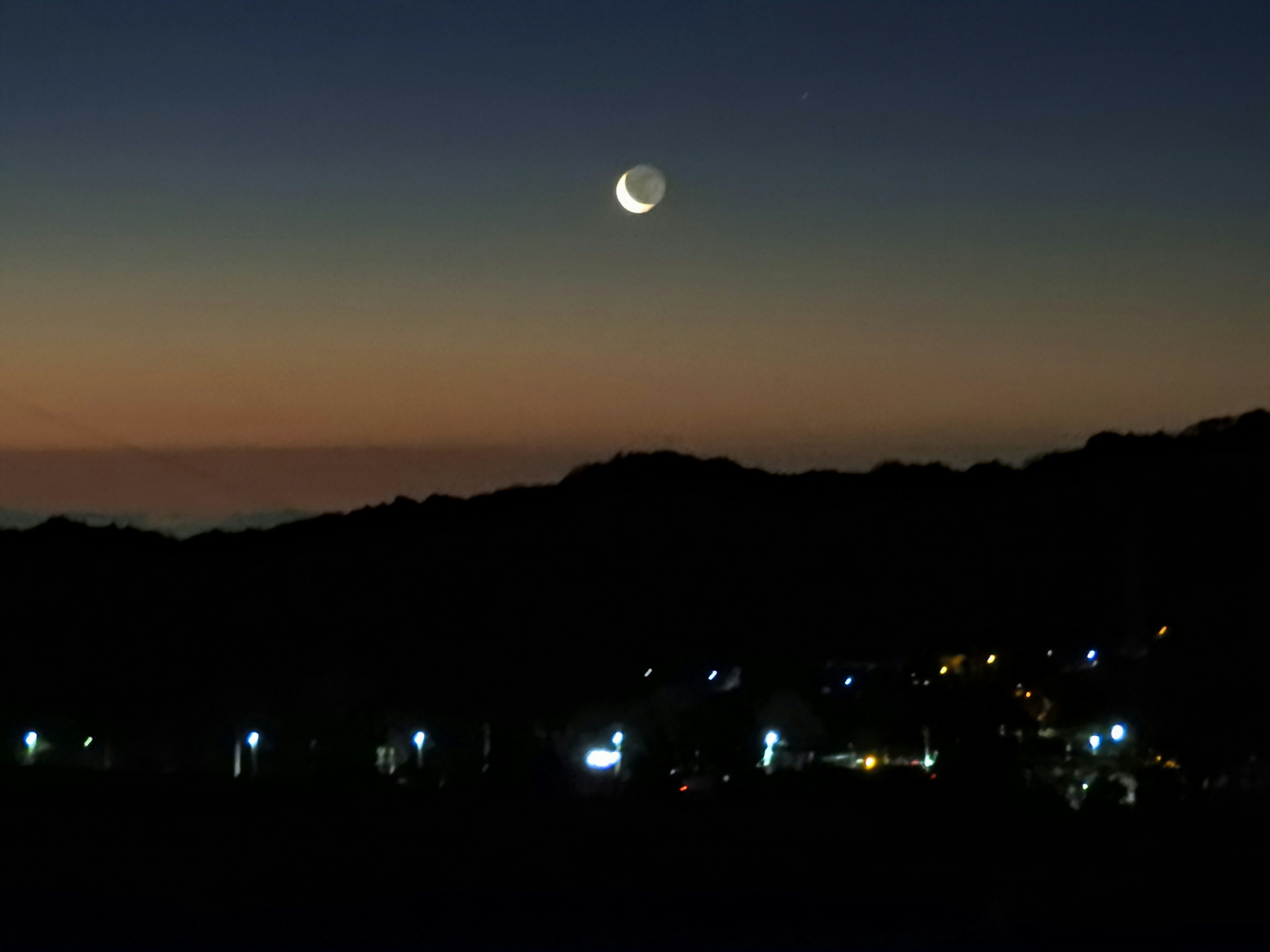 A beautiful twilight scene with a crescent moon in the sky