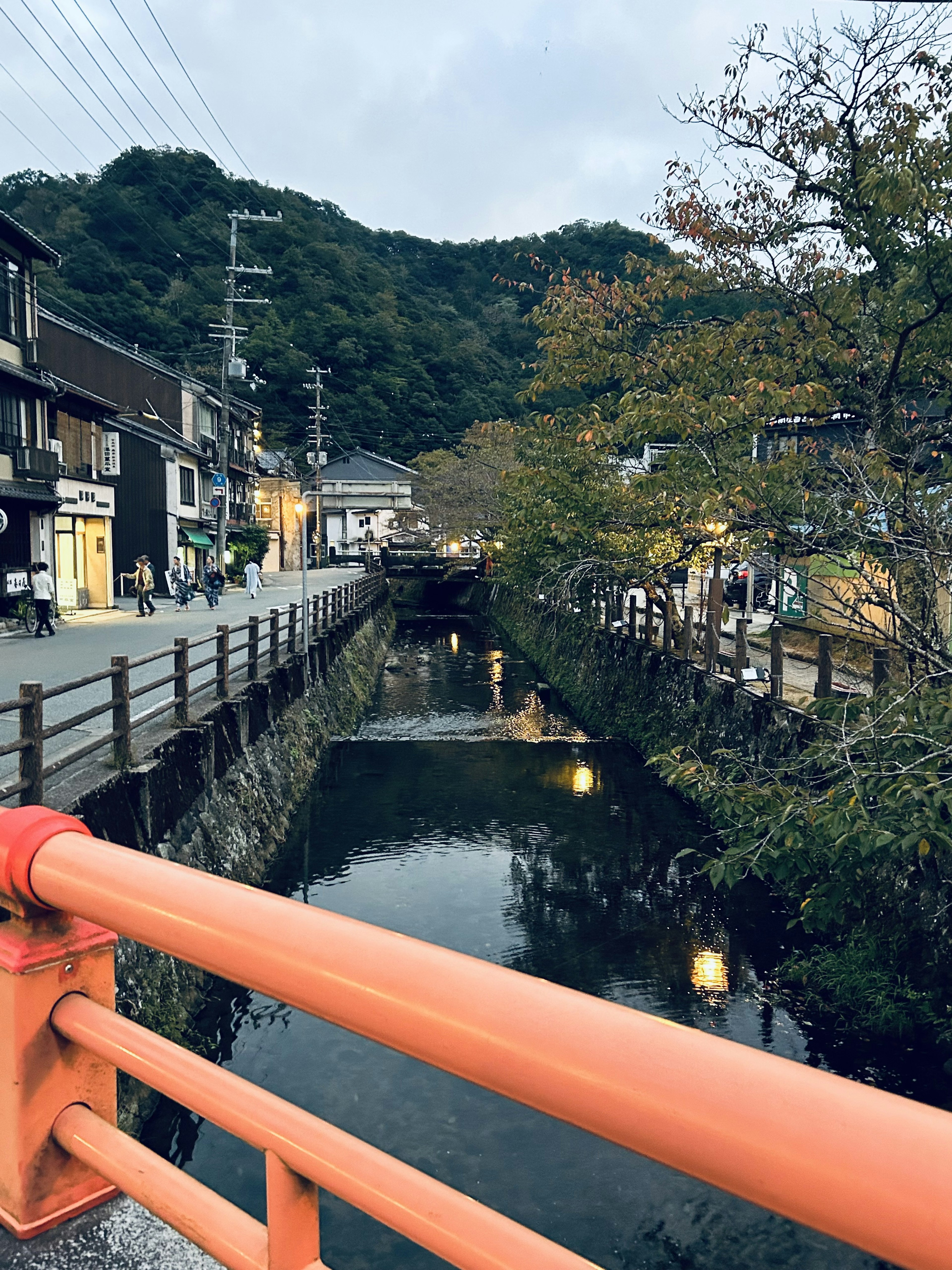 オレンジ色の橋から見た小川と周囲の商店街の風景