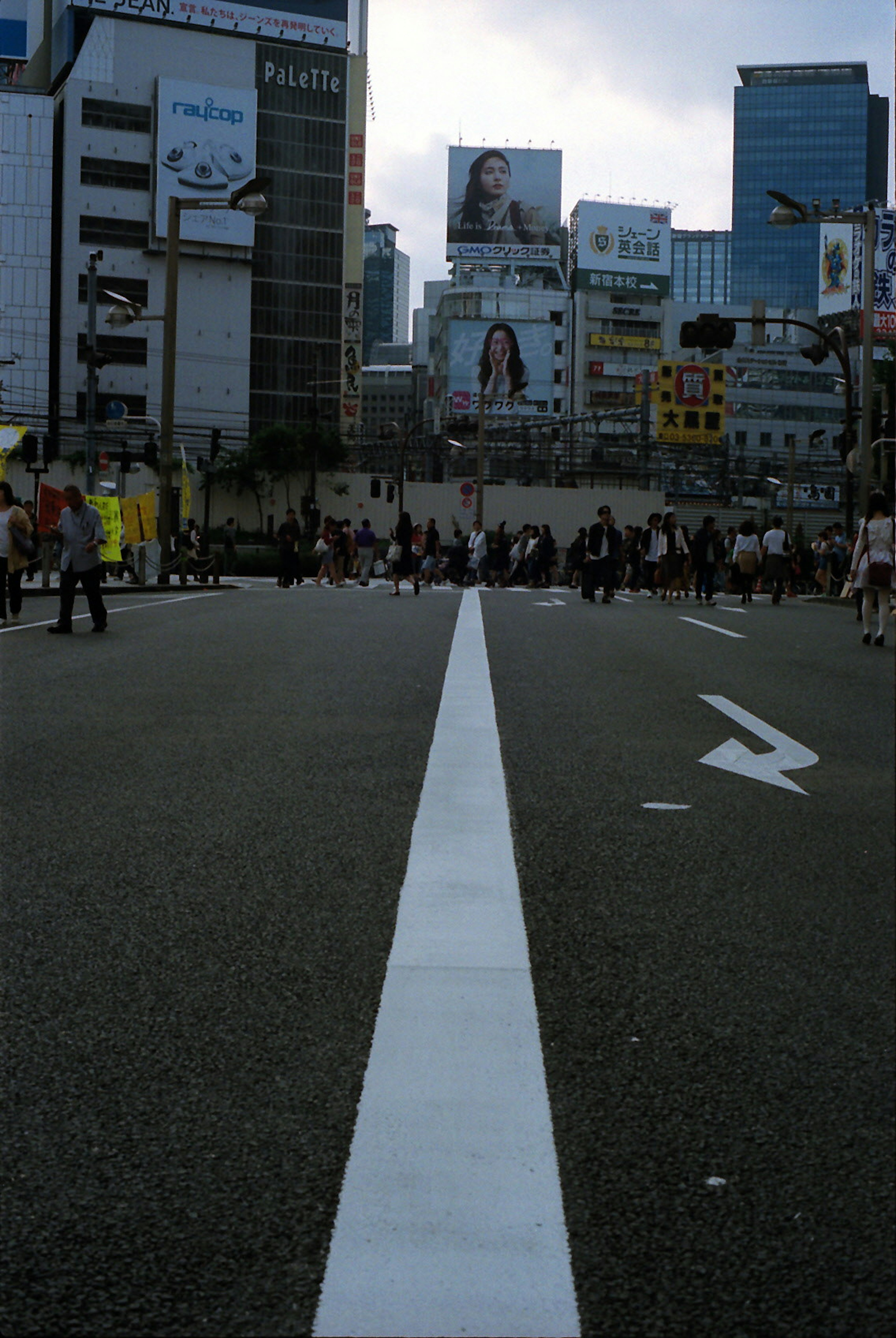 Wide city street with a central white line and crowds of people