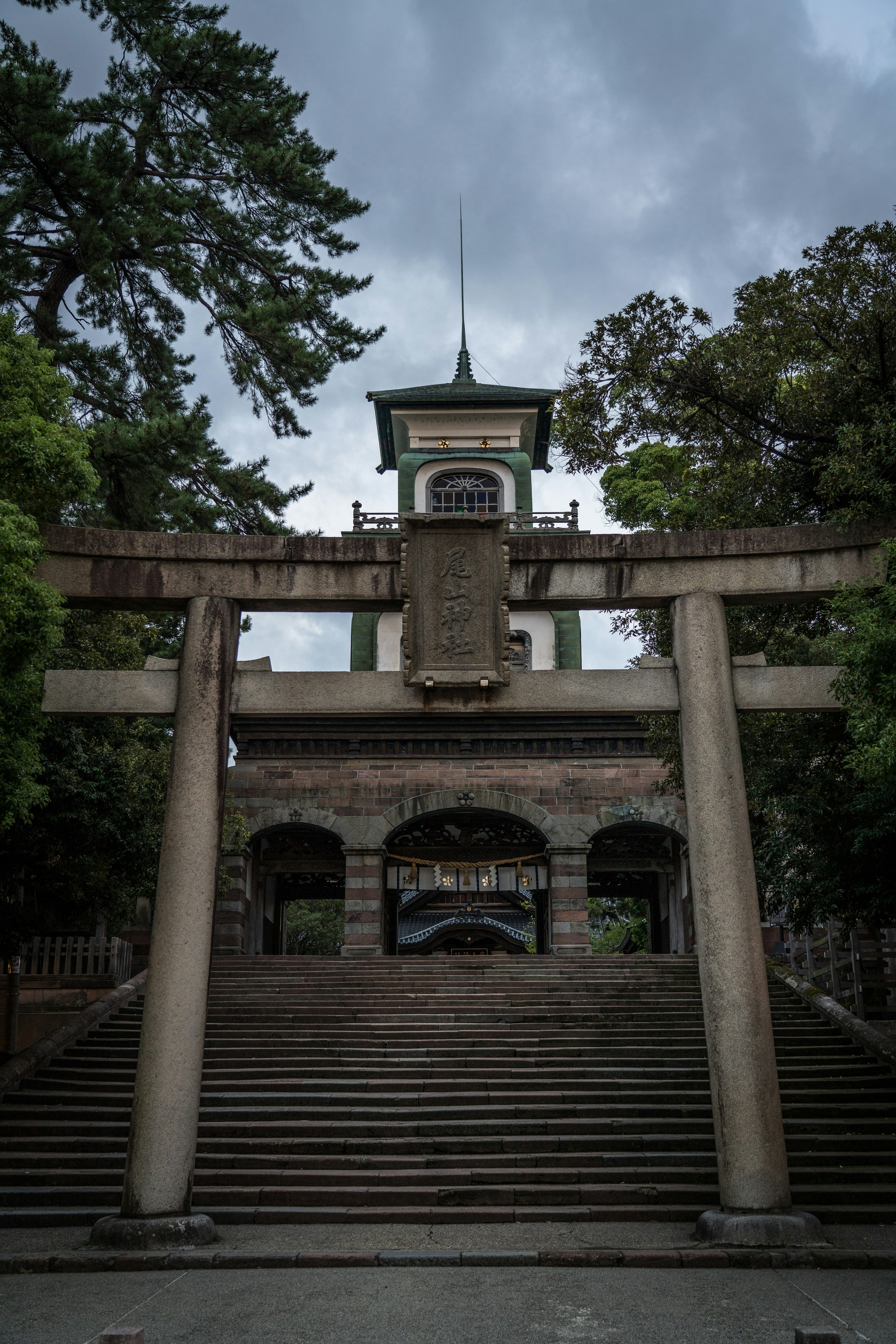 Stone staircase leading to a torii gate with a shrine building in the background