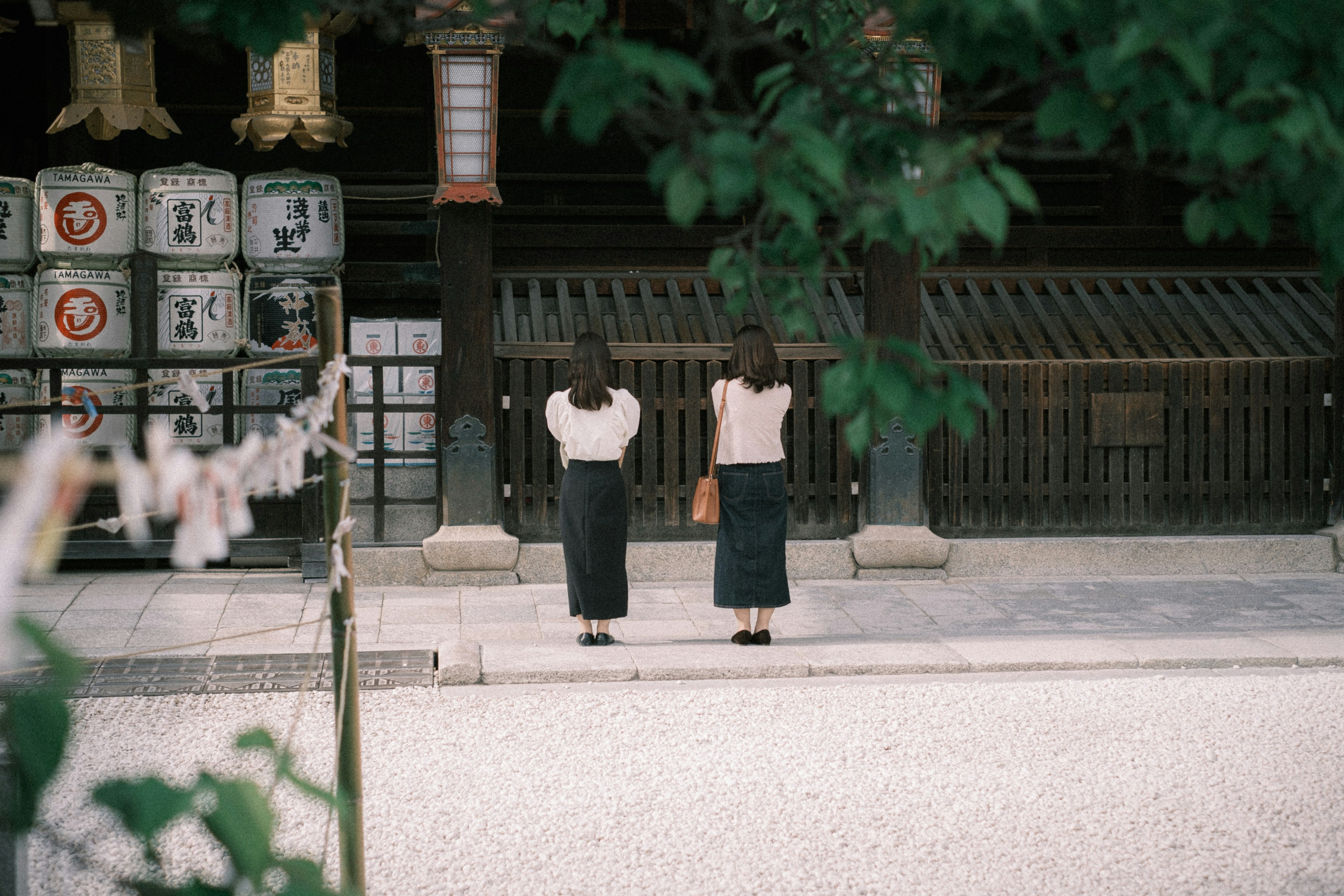 神社の前で祈る二人の女性が背を向けて立っている