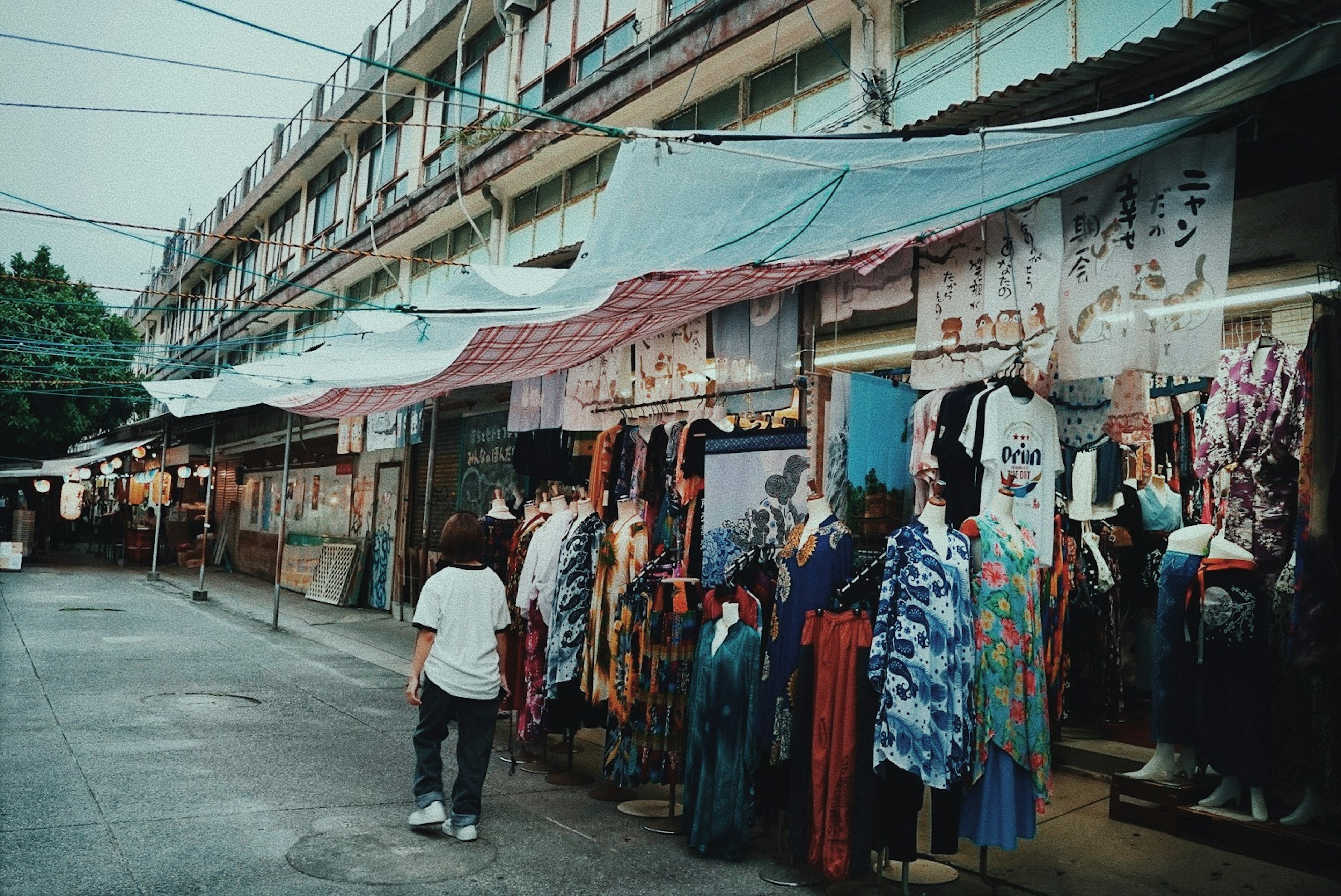 一个孩子在满是色彩斑斓衣物的市场街道上走