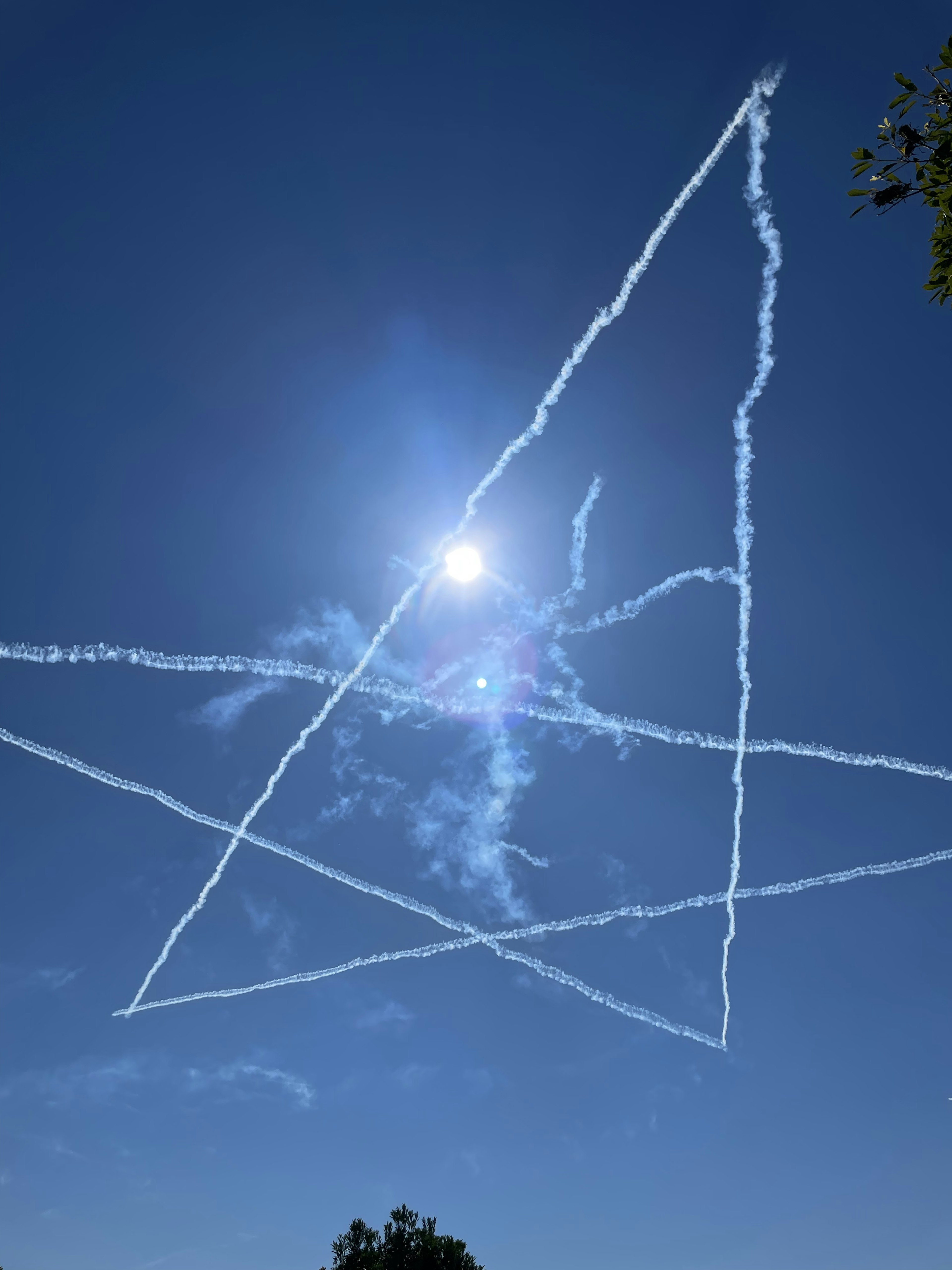 Un nuage de traînée en forme d'étoile dans un ciel bleu avec le soleil