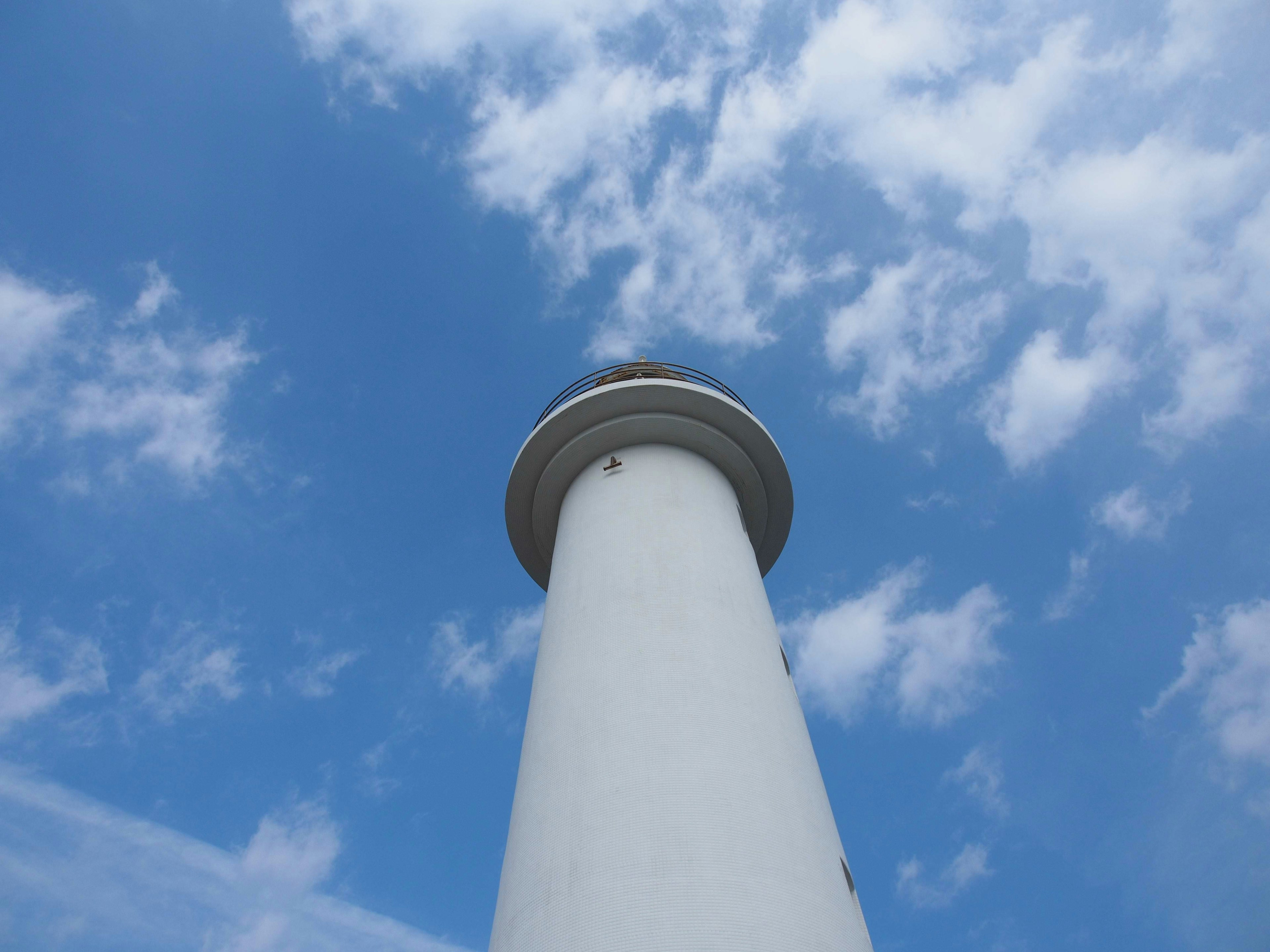 White lighthouse towering against a blue sky