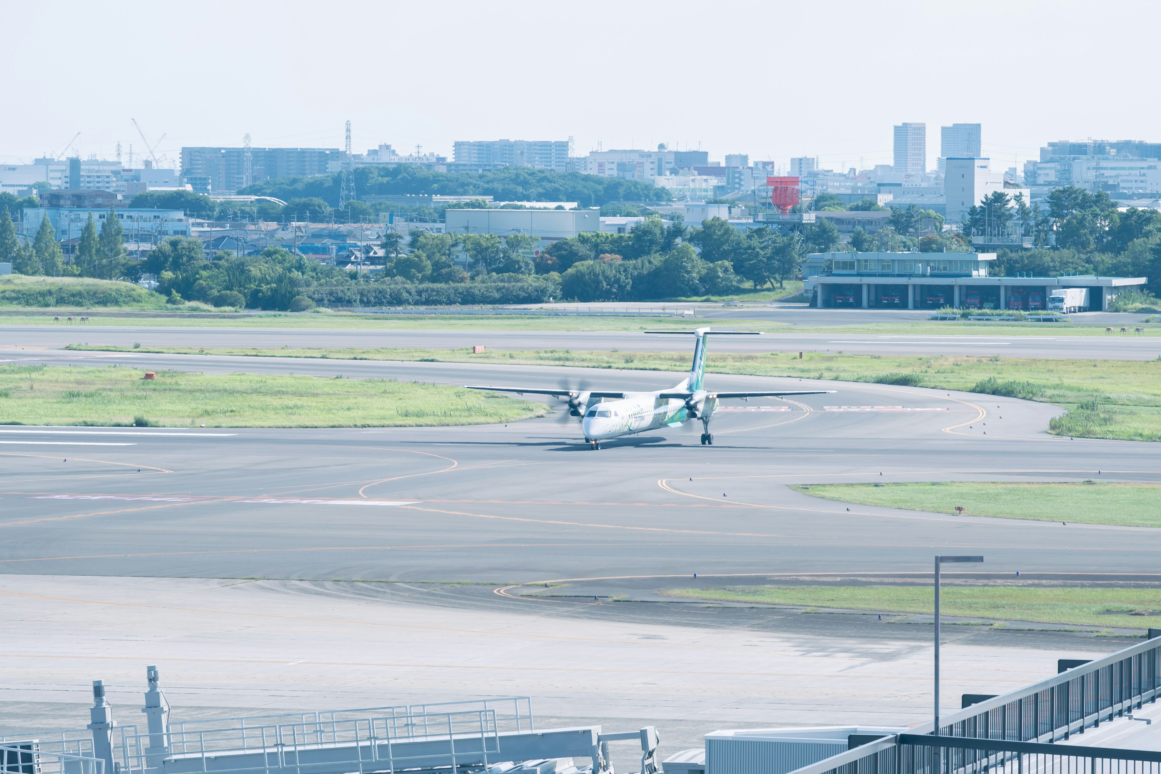 A small aircraft parked on the runway with a city skyline in the background