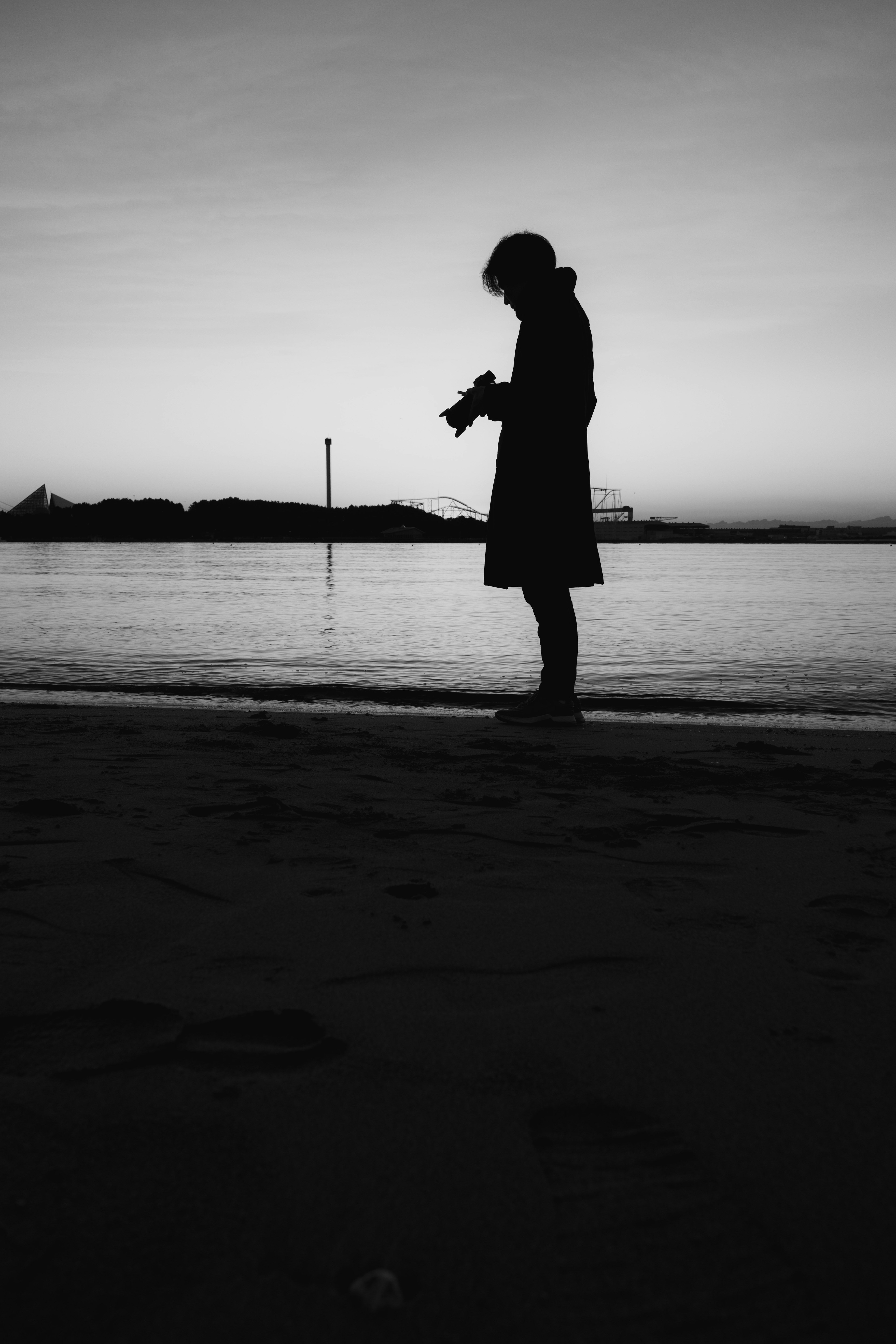 海辺でシルエットの女性が立っている夕暮れの風景