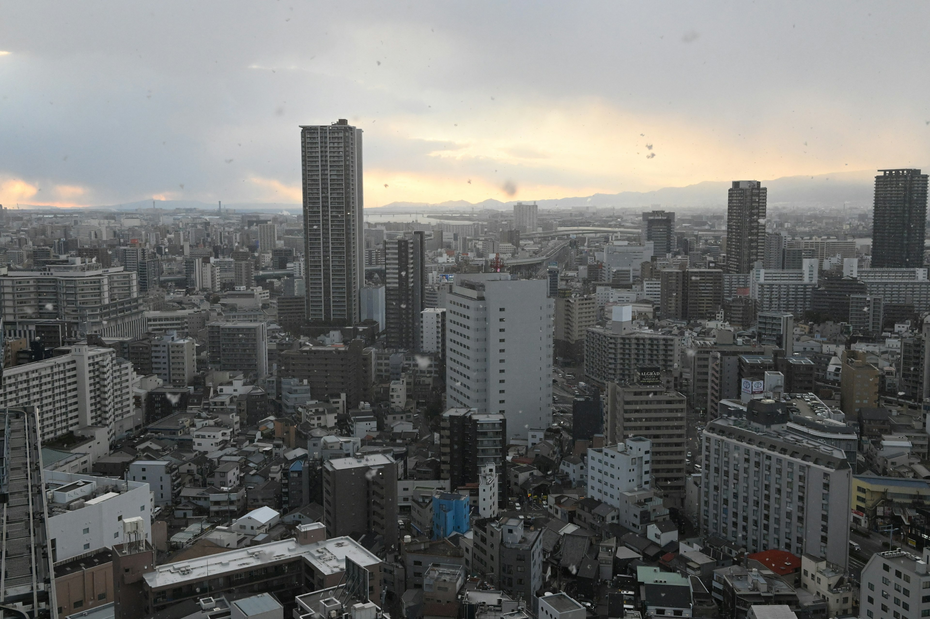 城市風景，高樓大廈在陰雲密布的天空下，夕陽光輝